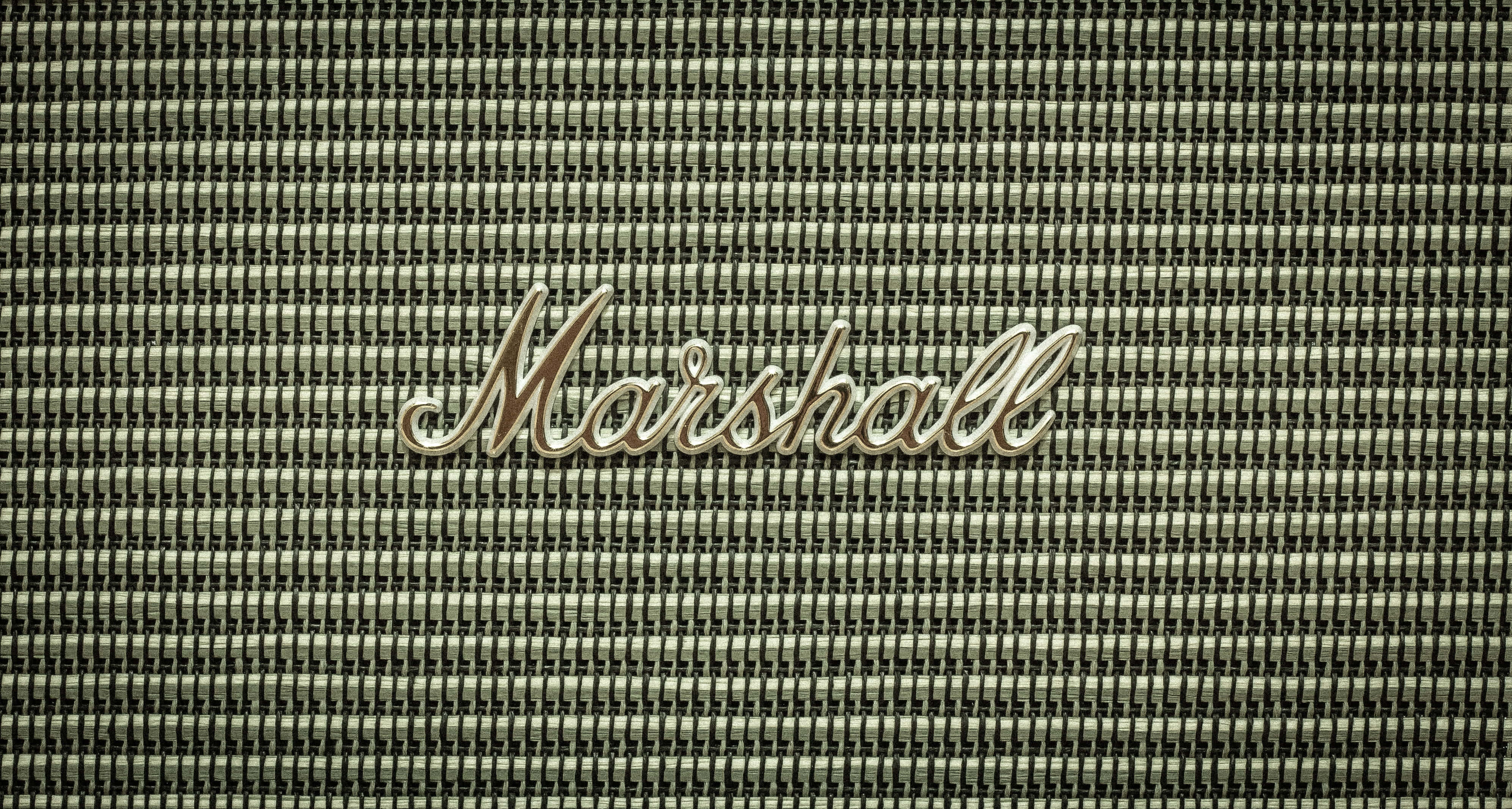 在Marshall的絕美風景中享受徒步之旅 壁紙 — 復古Marshall擴音器格柵的特寫，帶有金屬標誌，背景為紋理織物。