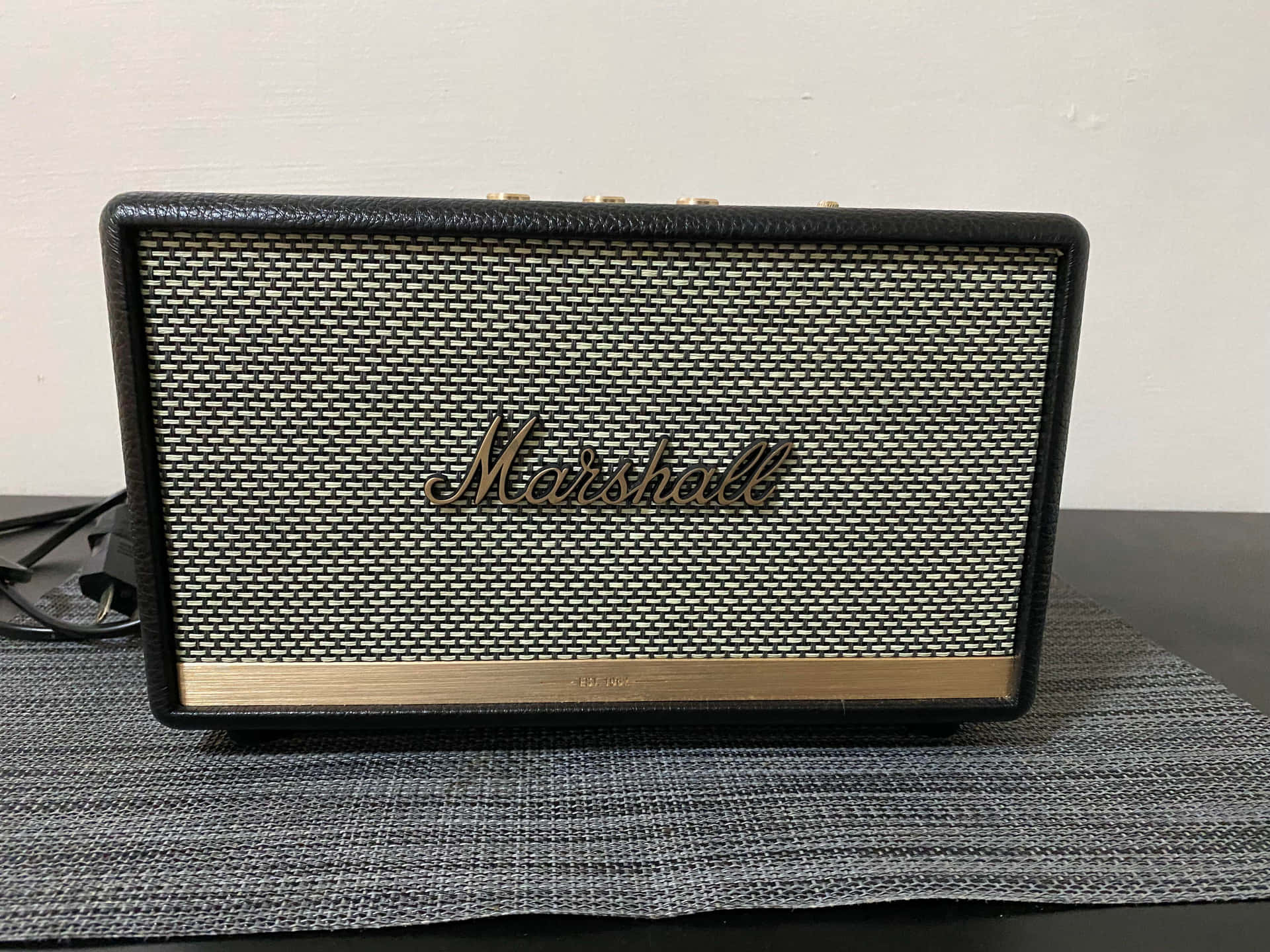 Marshall便攜式揚聲器放在灰色墊上，背景為白牆