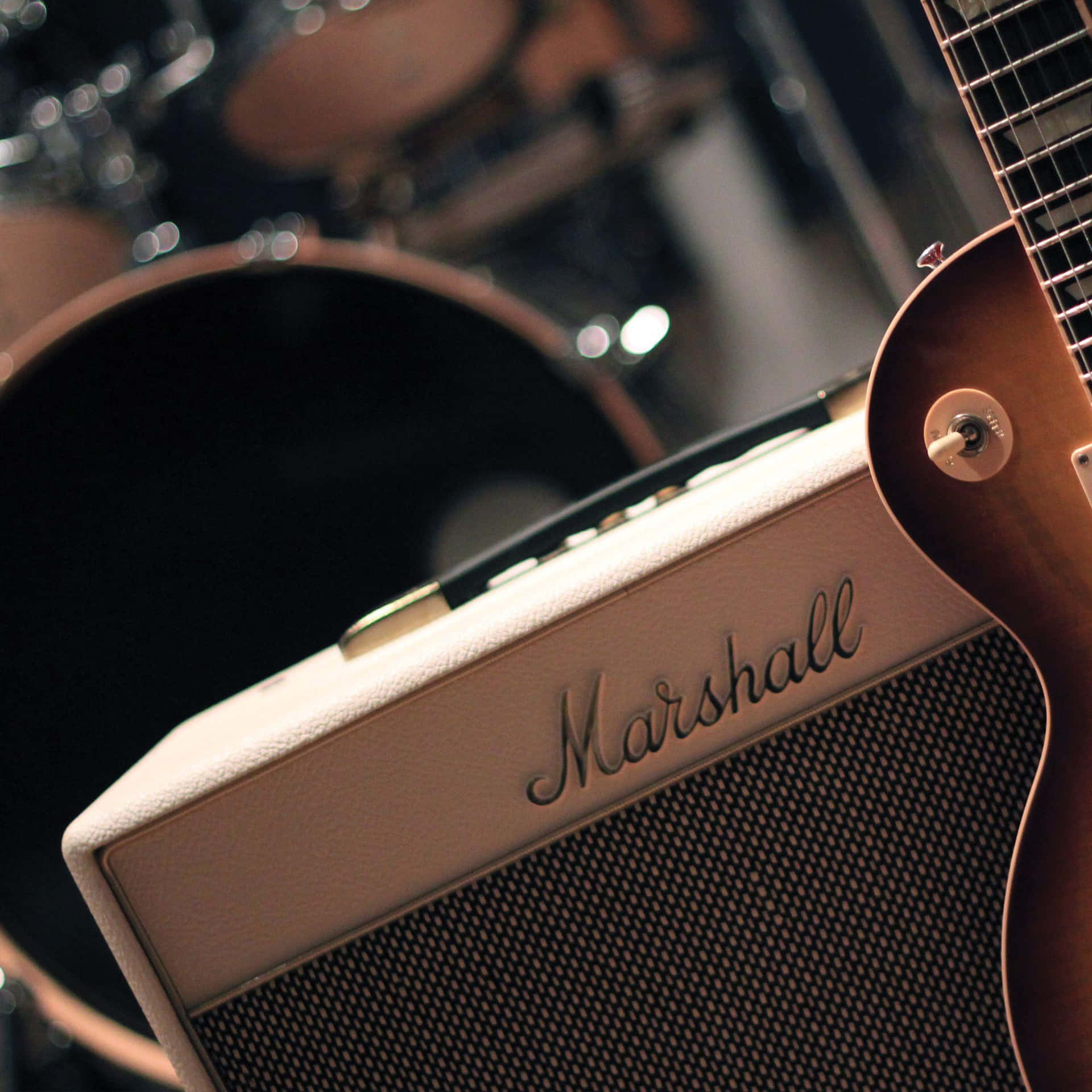 奶油色 Marshall 擴音器同 sunburst 結他，背景有鼓。