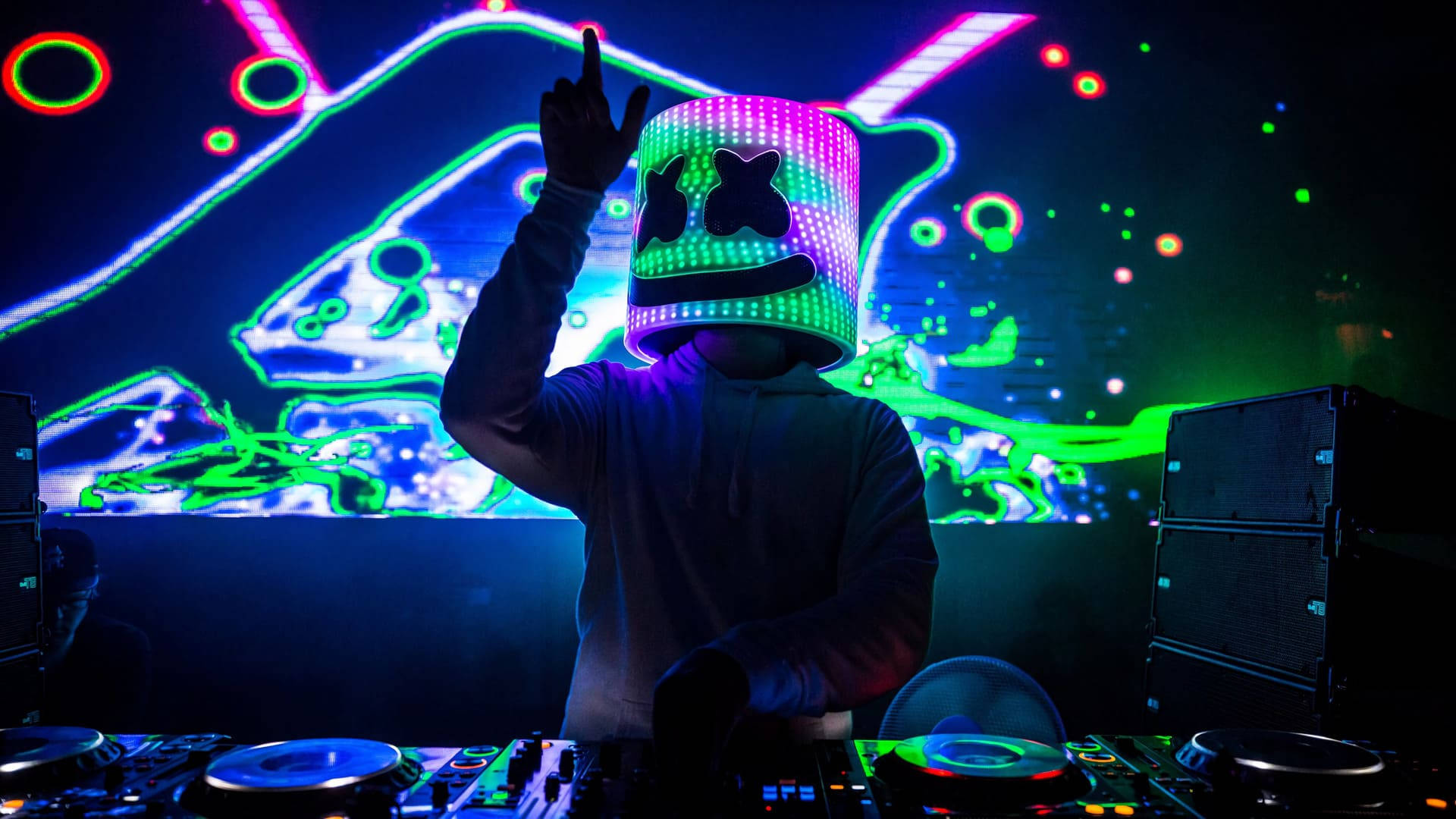 Marshmallow DJ 戴多色面具 壁紙 — 一名戴著發光LED棉花糖頭盔的DJ在霓虹燈照亮的夜店舞台上舉起手，背後有充滿活力的抽象視覺效果。