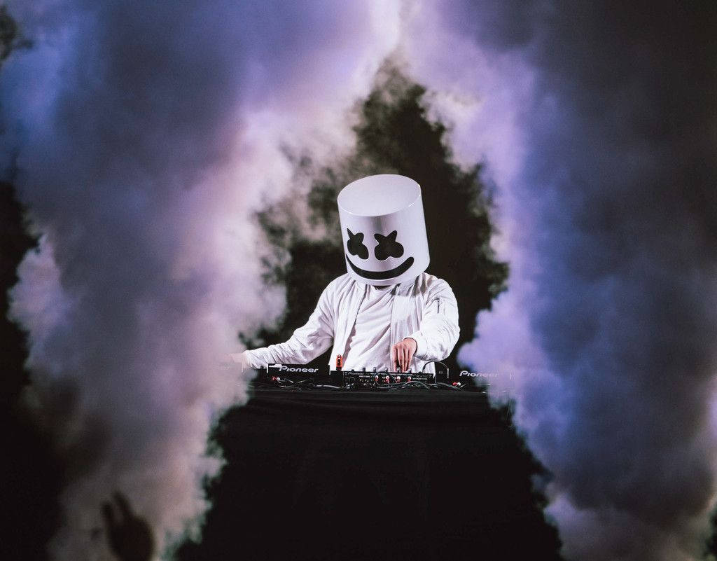 DJ Marshmello在演唱會上表演，伴隨著紫色煙霧效果。