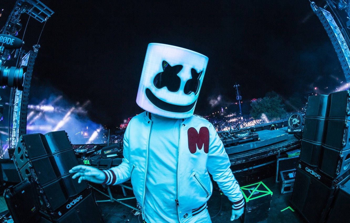 DJ Marshmello 戴著白色頭盔在夜間演唱會上表演，舞台燈光閃爍。