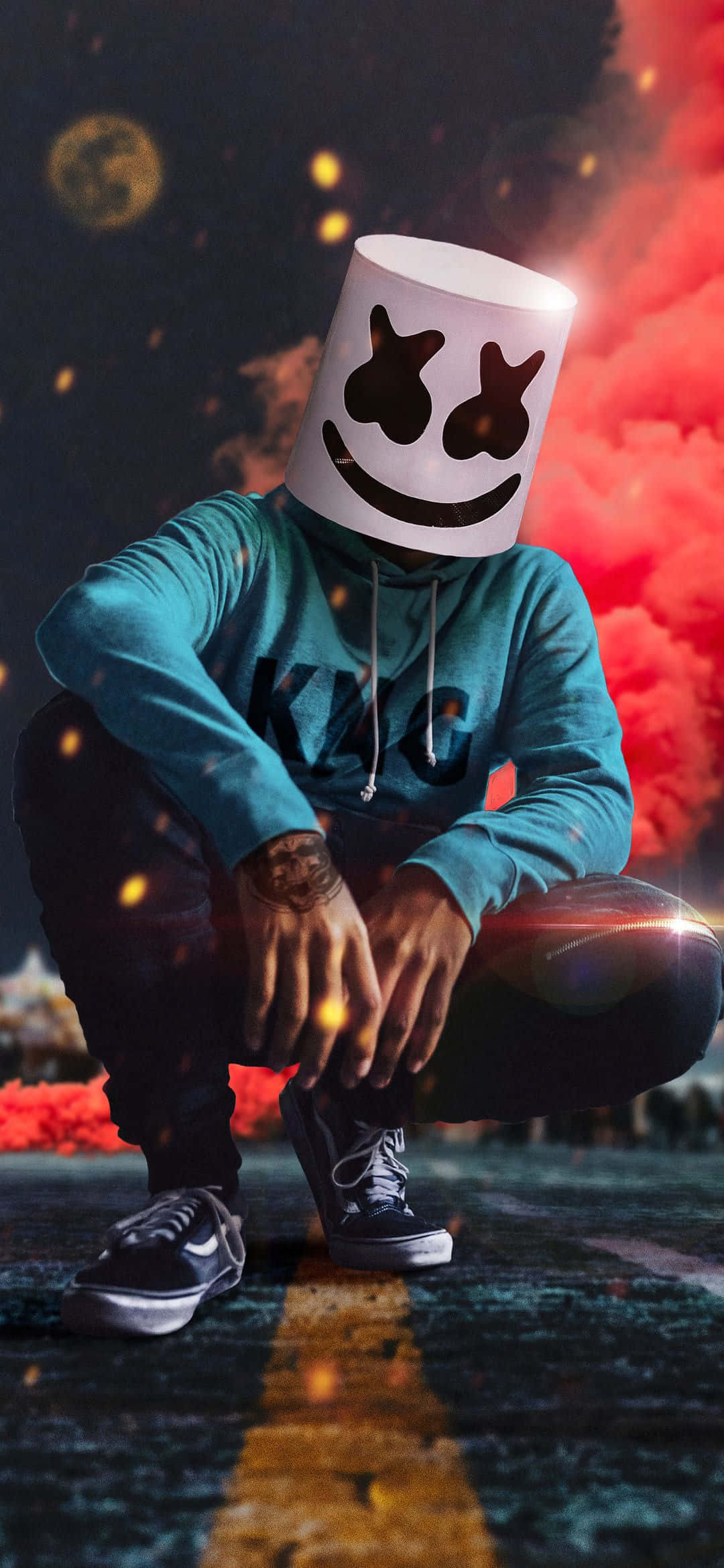 Marshmello 彩煙 4K 壁紙 — 一個穿著青綠色連帽衫、戴著標誌性棉花糖面具的人蹲在道路上，周圍有火紅色的煙霧和發光的粒子旋轉。