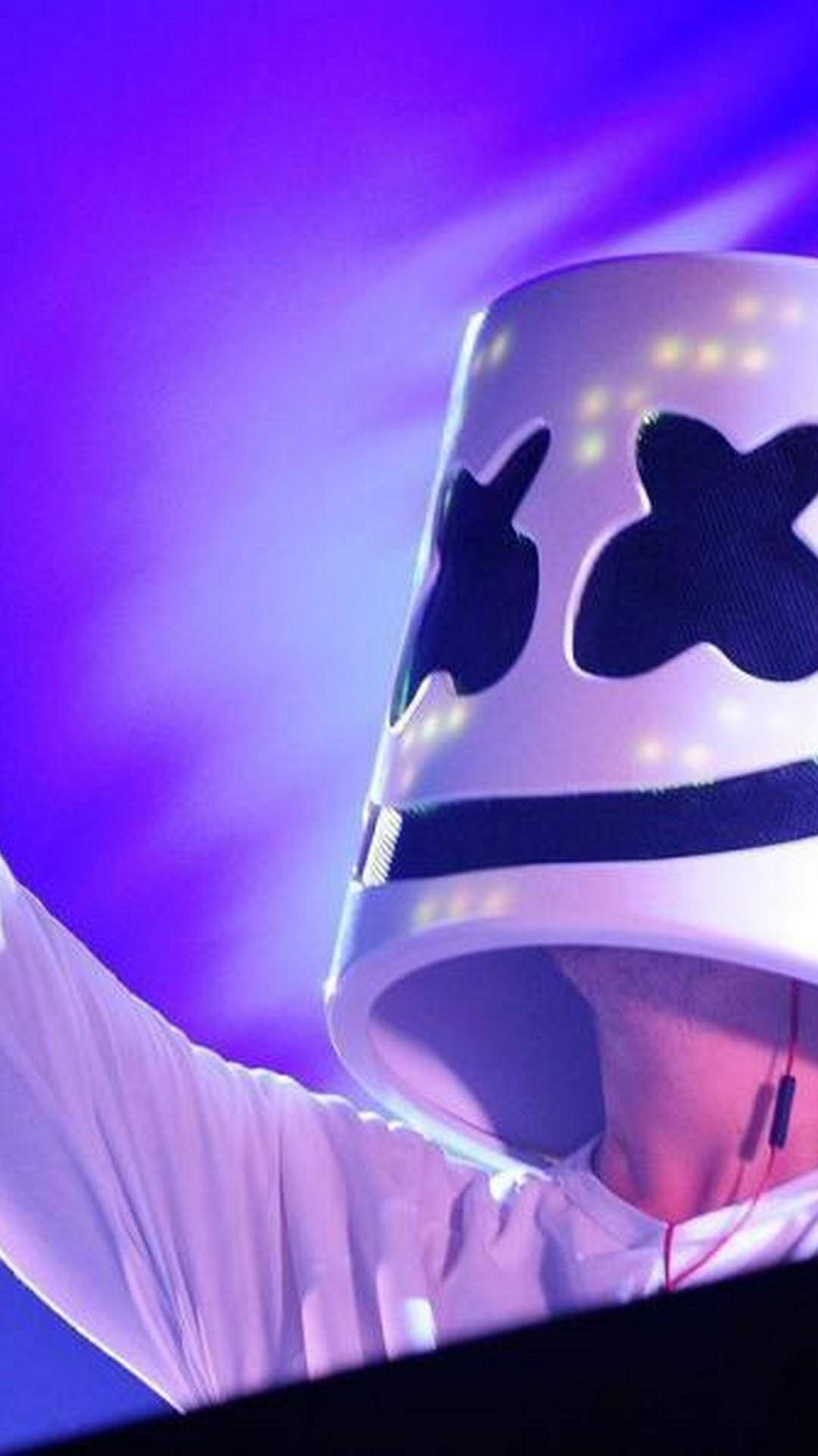 受Marshmello DJ啟發的刺激iPhone壁紙 壁紙 — 一位表演者戴著發光的白色頭盔，帶有黑色X眼睛，在充滿活力的紫色舞台背景下舉起手臂。