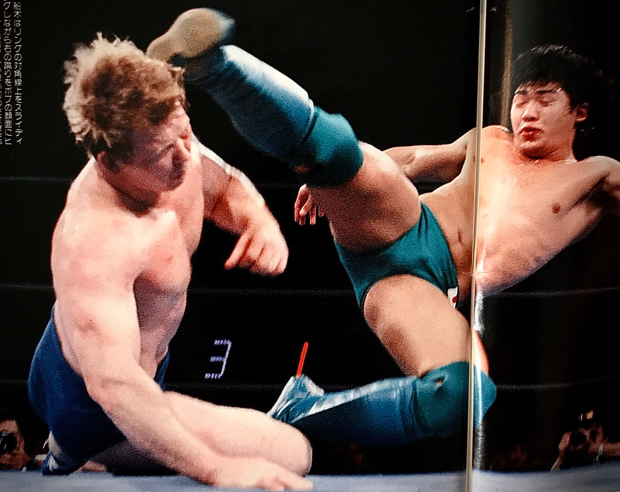 Masakatsu Funaki對決Bob Backlund 1989 UWF賽事 壁紙 — 兩名肌肉發達的摔角手穿著藍色短褲，在明亮的場館燈光下於擂台上激烈纏鬥。