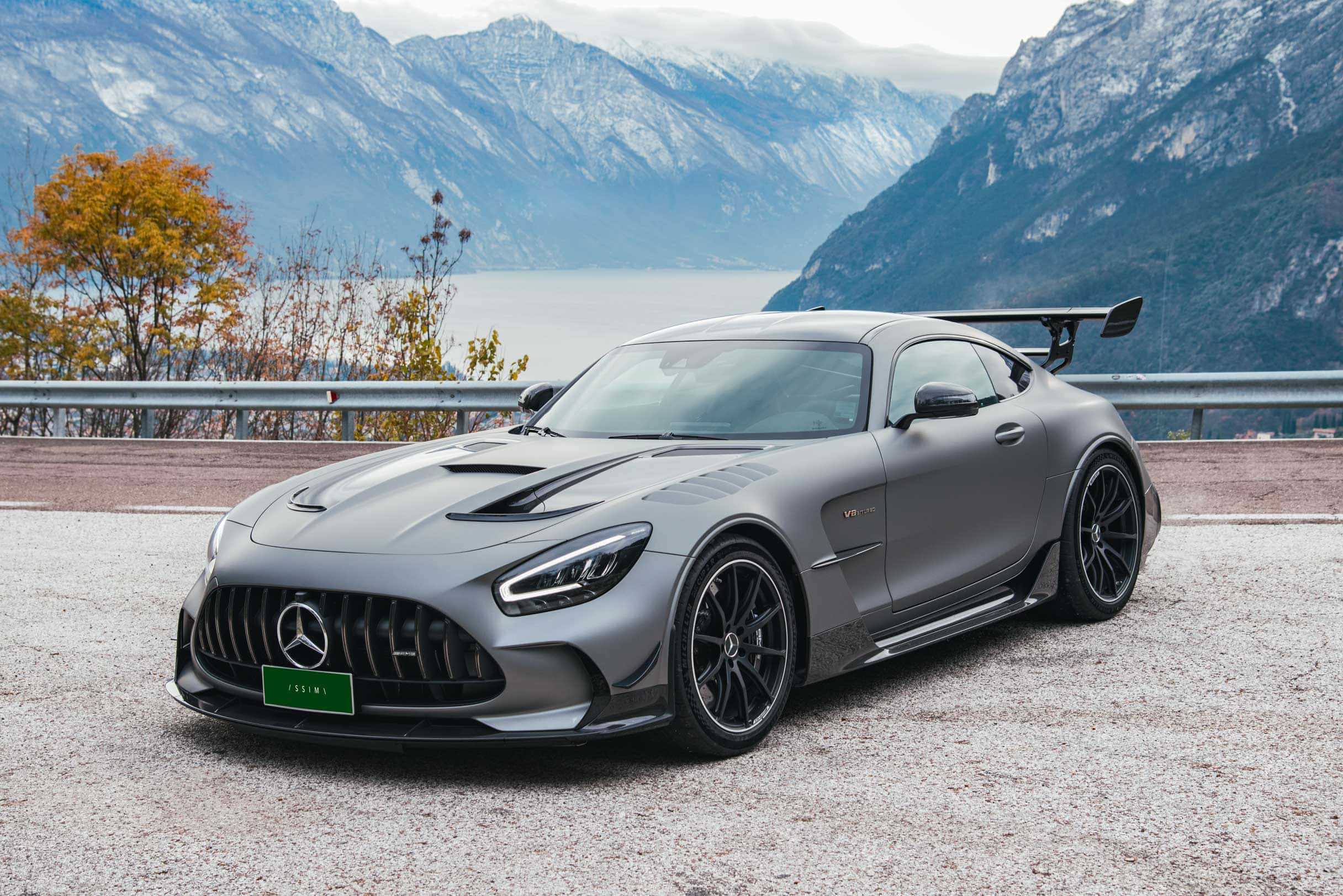 Mercedes Benz Amg Gt 桌布 壁紙 — 一輛啞光灰色的 Mercedes-AMG GT Black Series 跑車停在碎石觀景點上，背景是白雪覆蓋的山脈和湖泊。