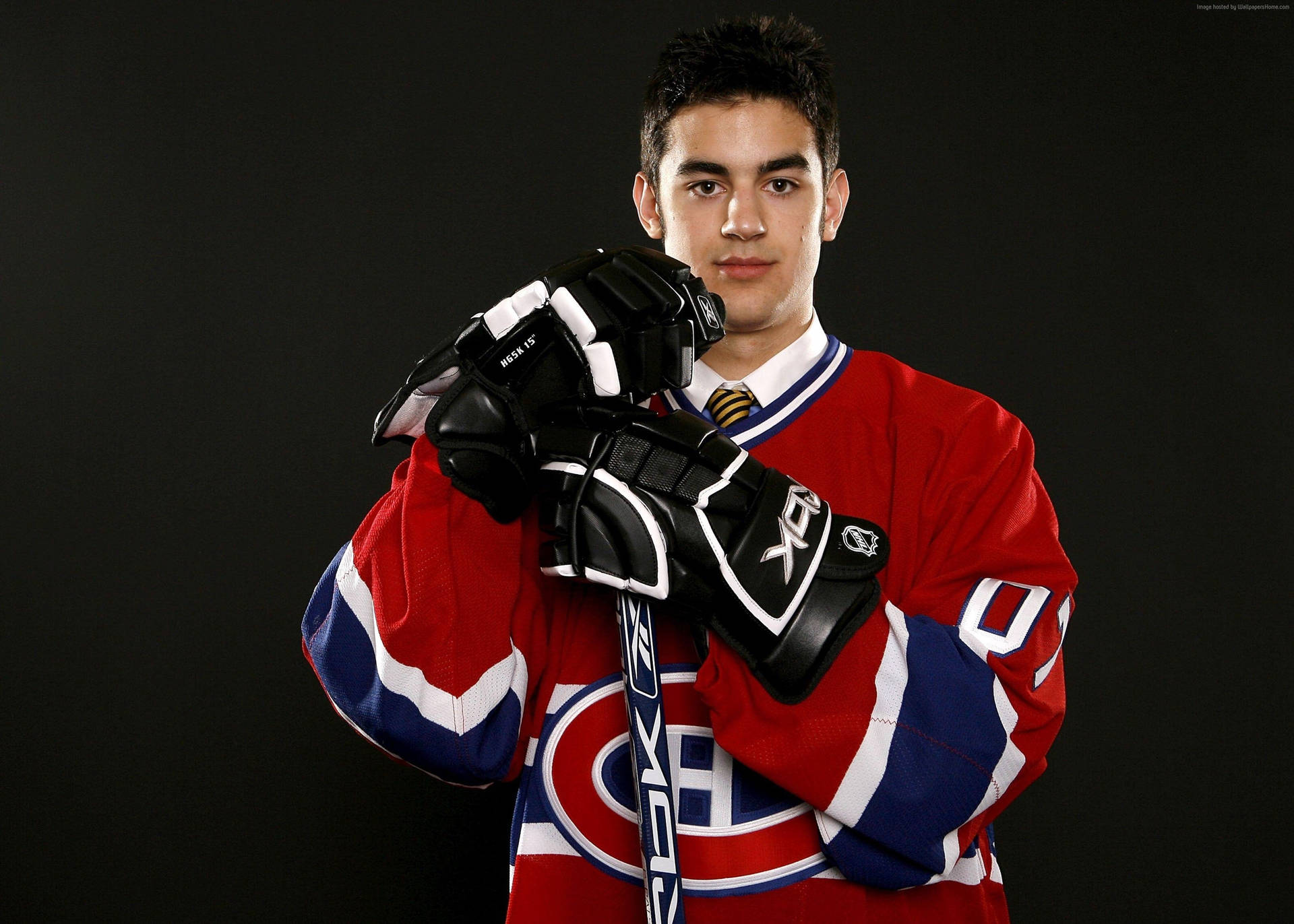 Max Pacioretty 獲選照片 壁紙 — 一名年輕的冰球運動員身穿紅色蒙特利爾加拿大人隊球衣，在深色工作室背景下手持球桿和手套。