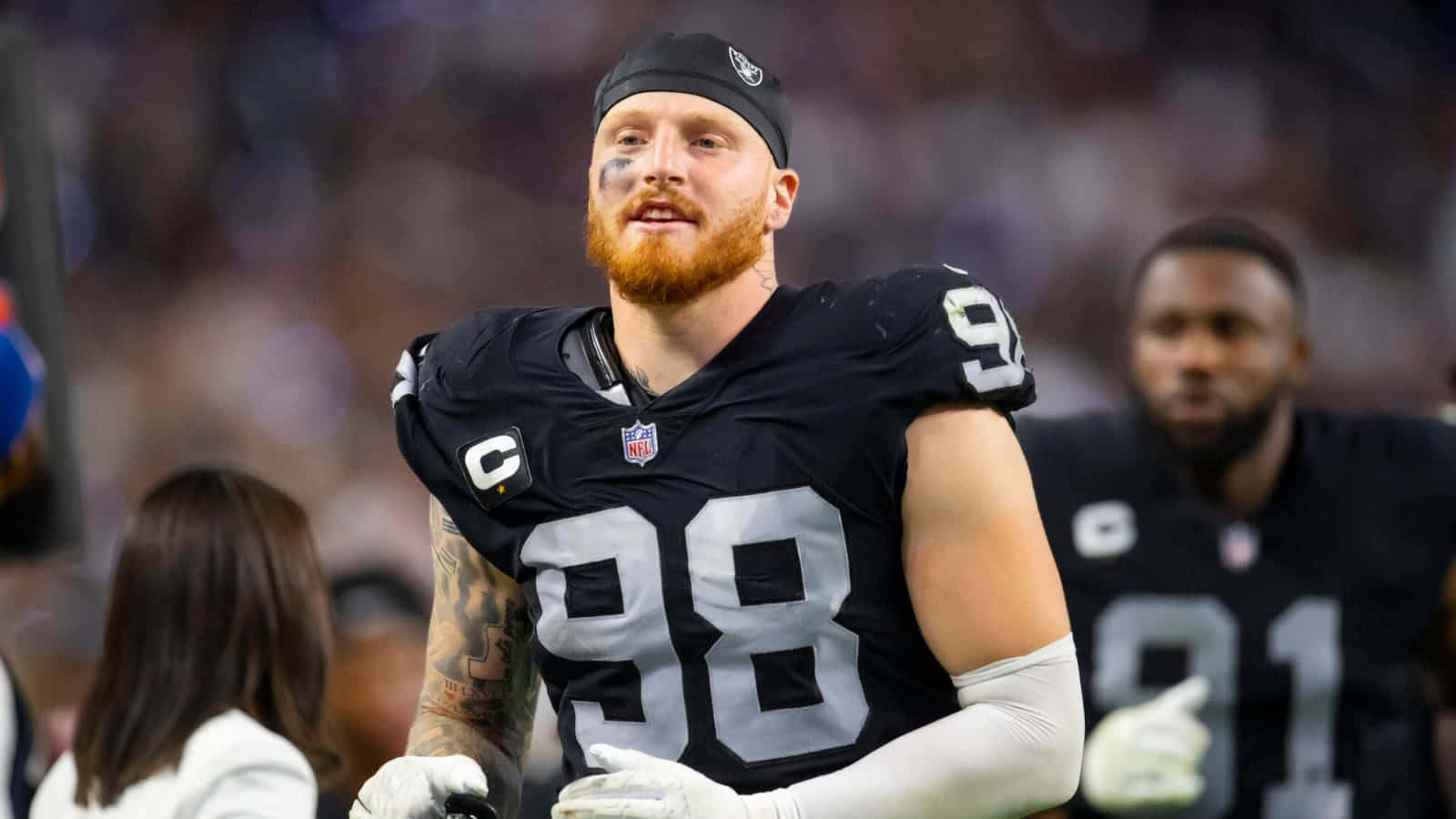 NFL球員身穿黑色98號球衣，留著紅色鬍鬚，在夜間足球場上。