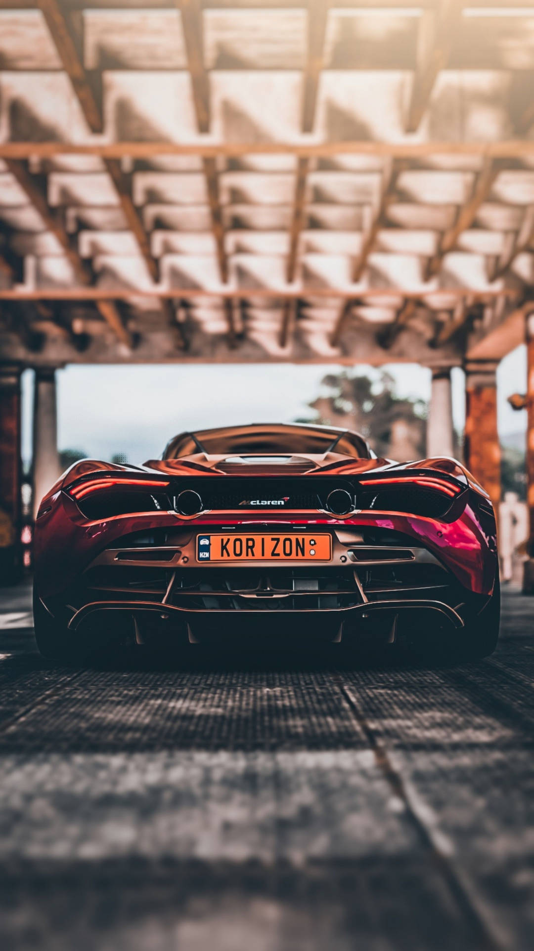 紅色McLaren跑車停在混凝土天橋下，夕陽西下。