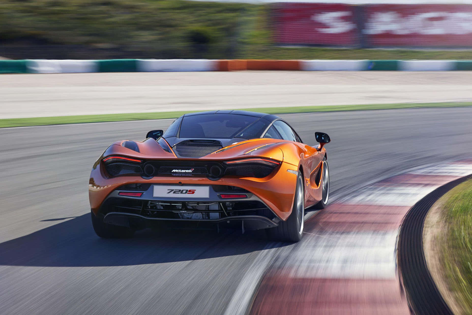 橙色McLaren 720S賽車在日落時分的賽道上疾馳。