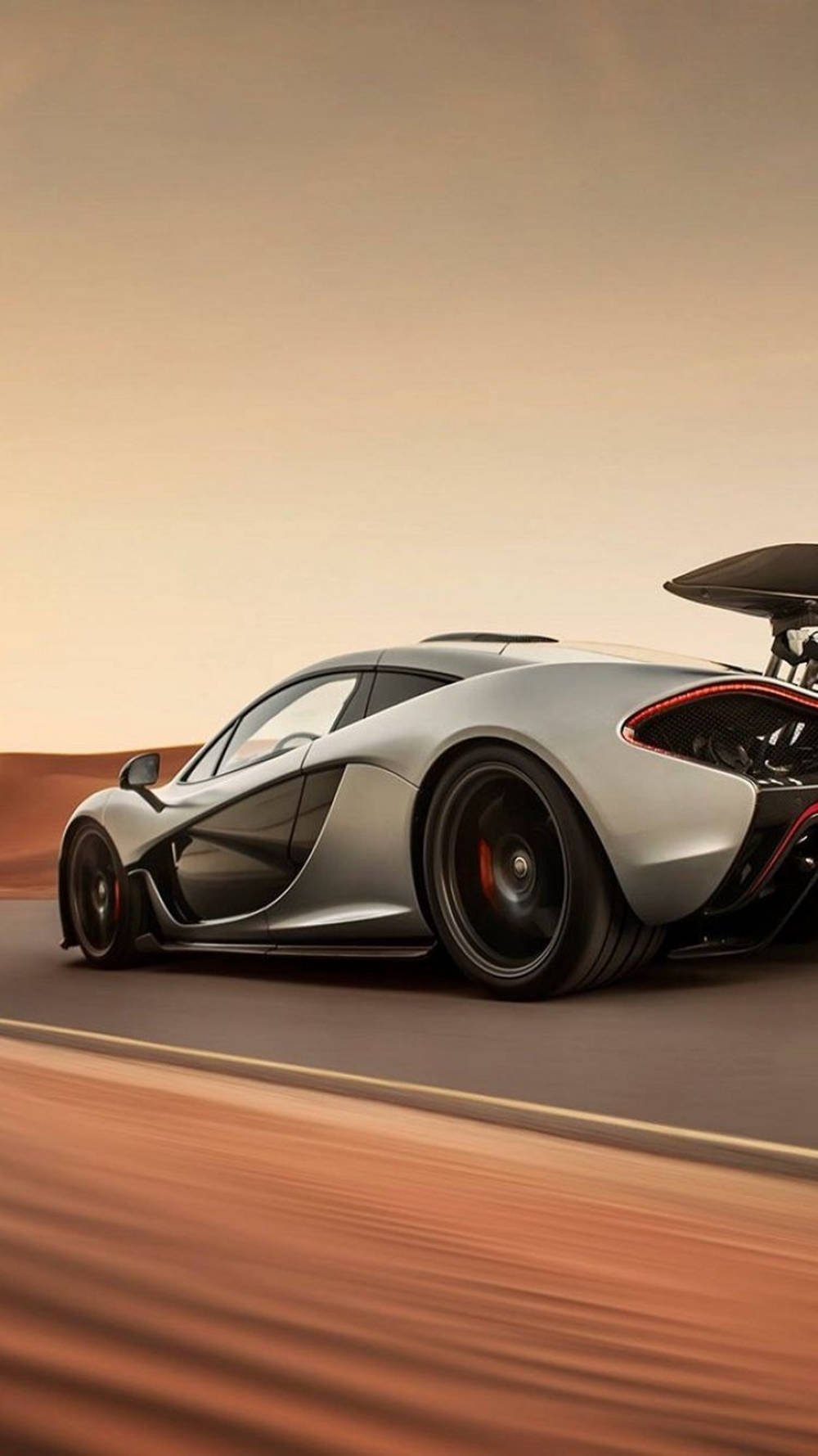 銀色McLaren P1在沙漠公路上飛馳，日落時分。