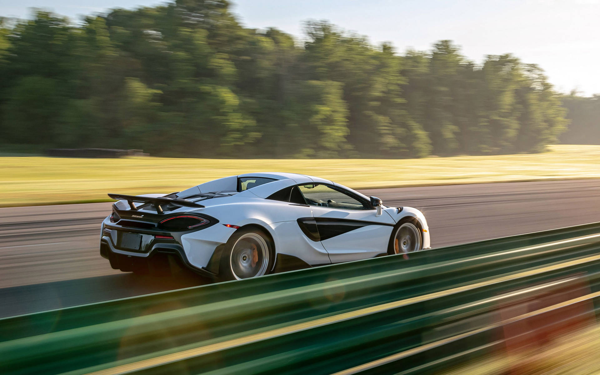 白色McLaren賽車在賽道上高速行駛，帶有動態模糊效果