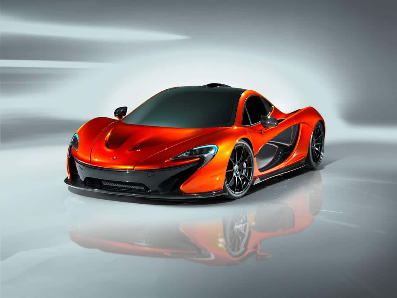 橙色McLaren P1超級跑車，帶有黑色飾邊，映照在反光的工作室地板上。