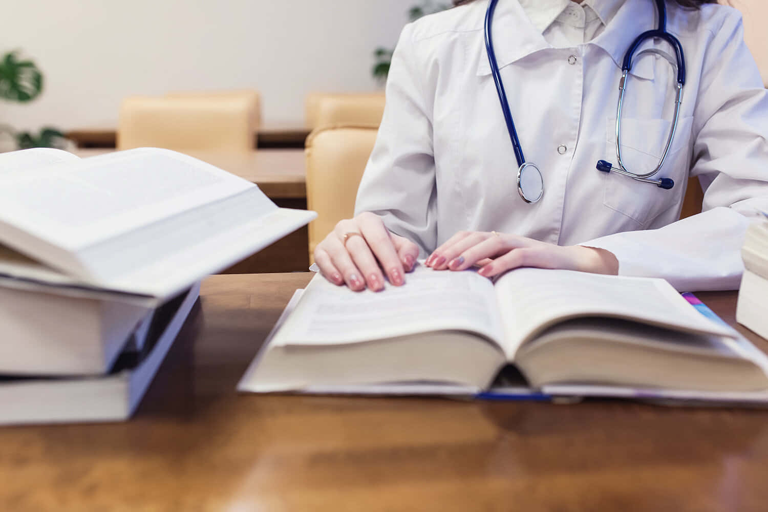 醫生在辦公室的木桌上查閱醫學書籍。