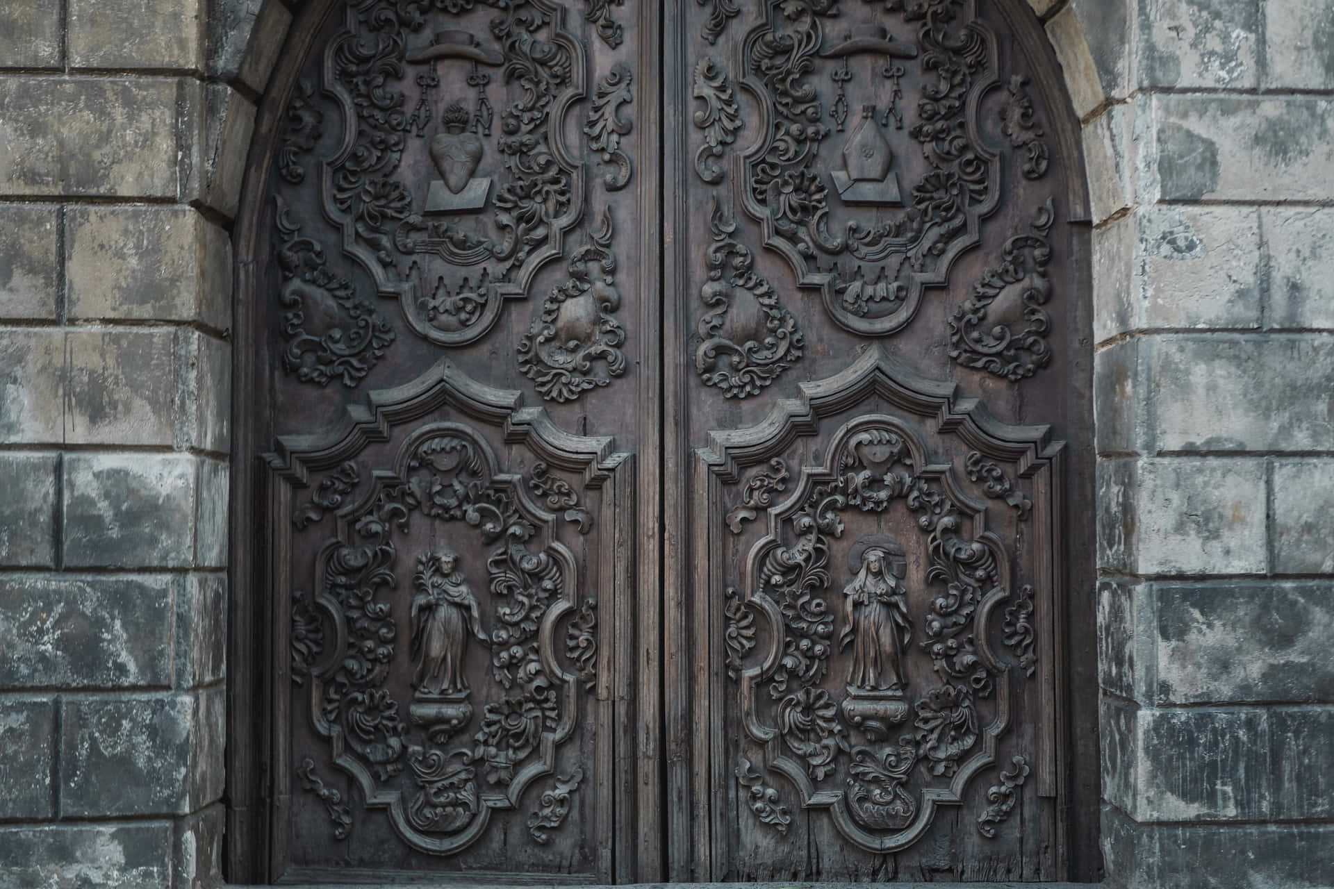 風化的石牆框住了雕刻精美的木製教堂門。