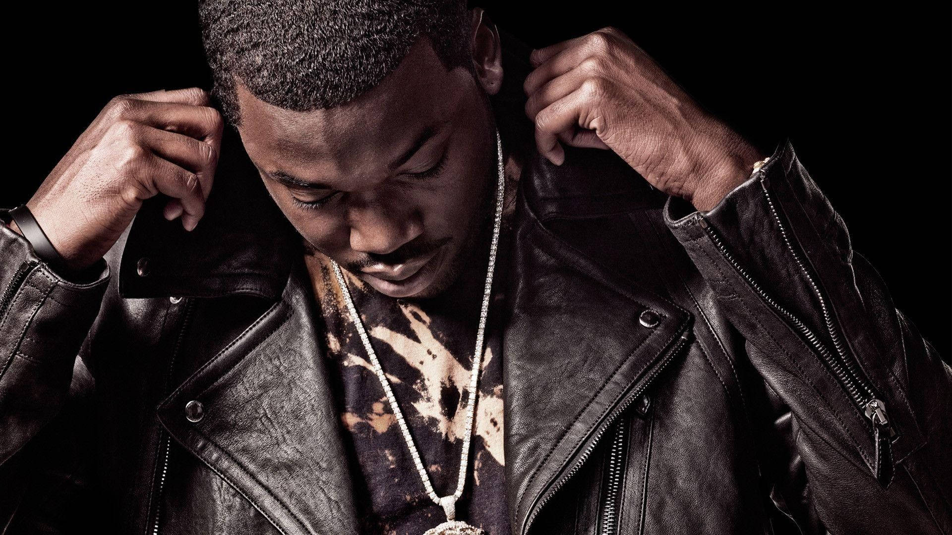 Meek Mill 皮夾克造型壁紙 壁紙 — 一個穿著黑色皮褸的男人在黑暗背景中，戲劇性燈光下調整衣領。