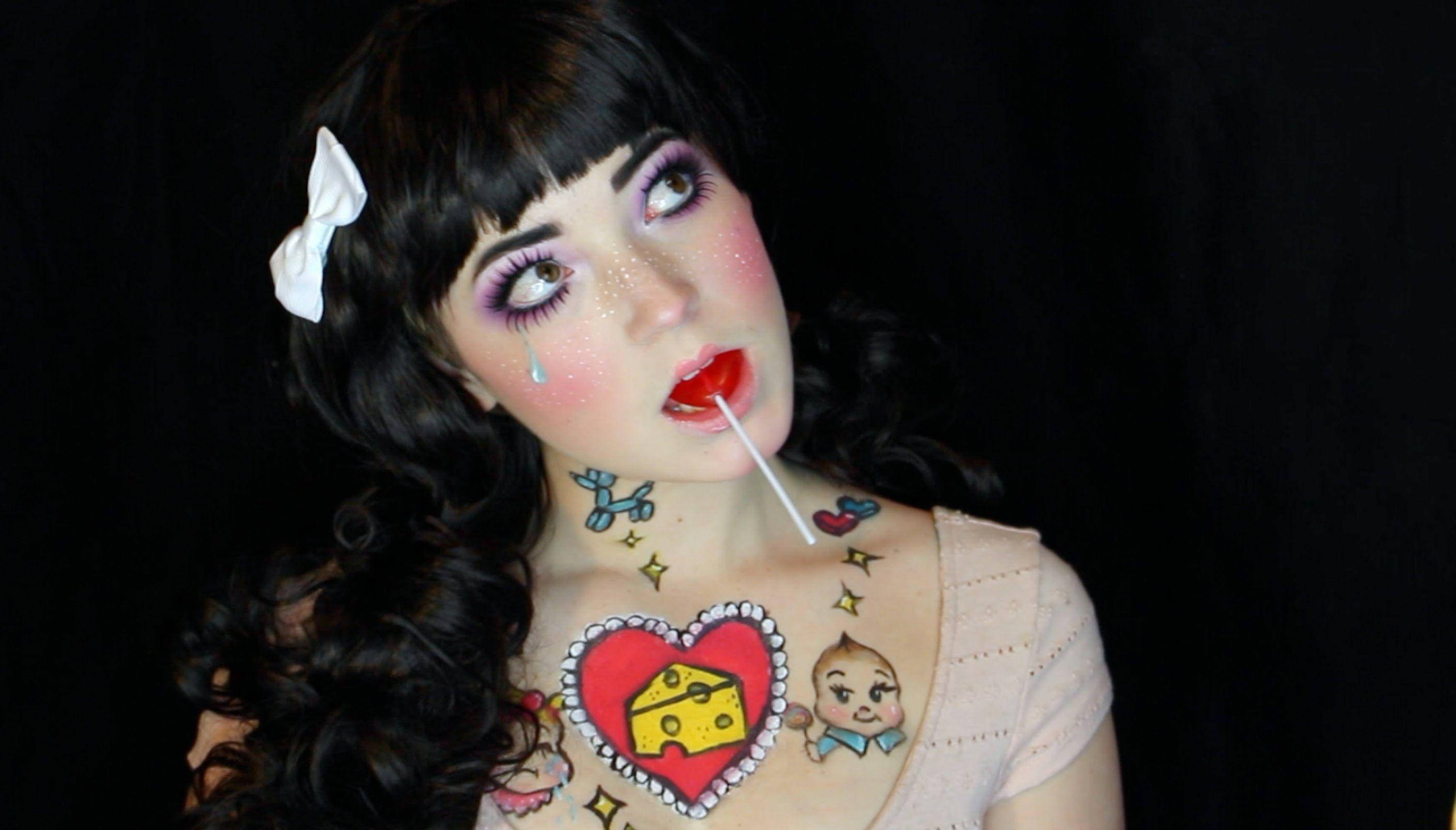 Melanie Martinez 起司 壁紙 — 一位擁有深色捲髮和白色蝴蝶結的女性，在黑色背景前舔著棒棒糖，頸部和胸部有色彩繽紛的卡通紋身。