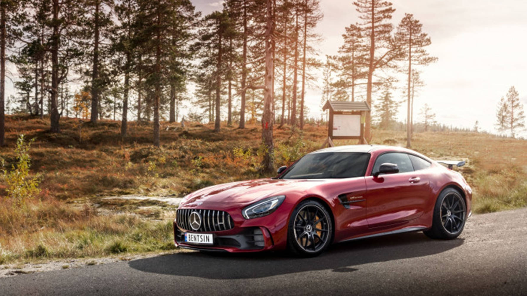 日落時分停泊在森林道路上的紅色 Mercedes-AMG GT R。