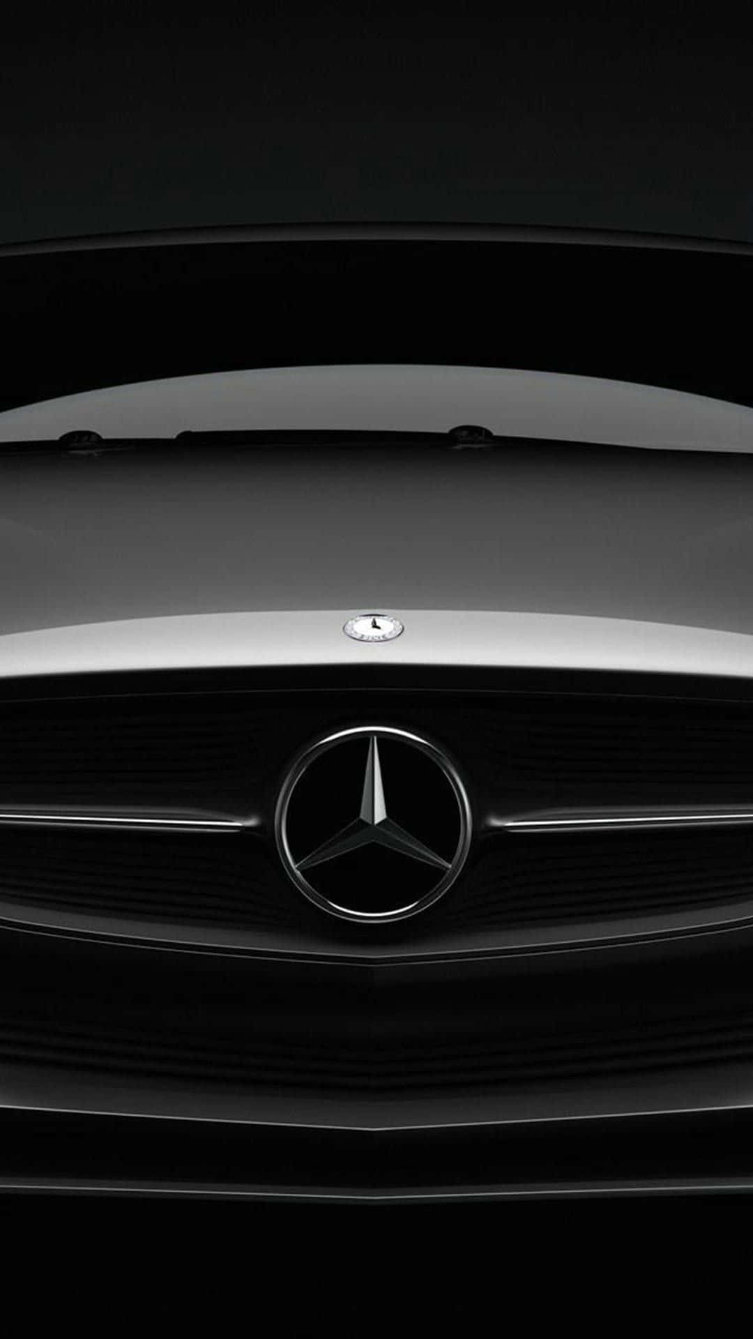 查看最新 Mercedes-Benz iPhone 壁紙 — 在戲劇性的工作室燈光下，時尚黑色平治鬼面罩帶有鍍鉻星徽標的 close-up。