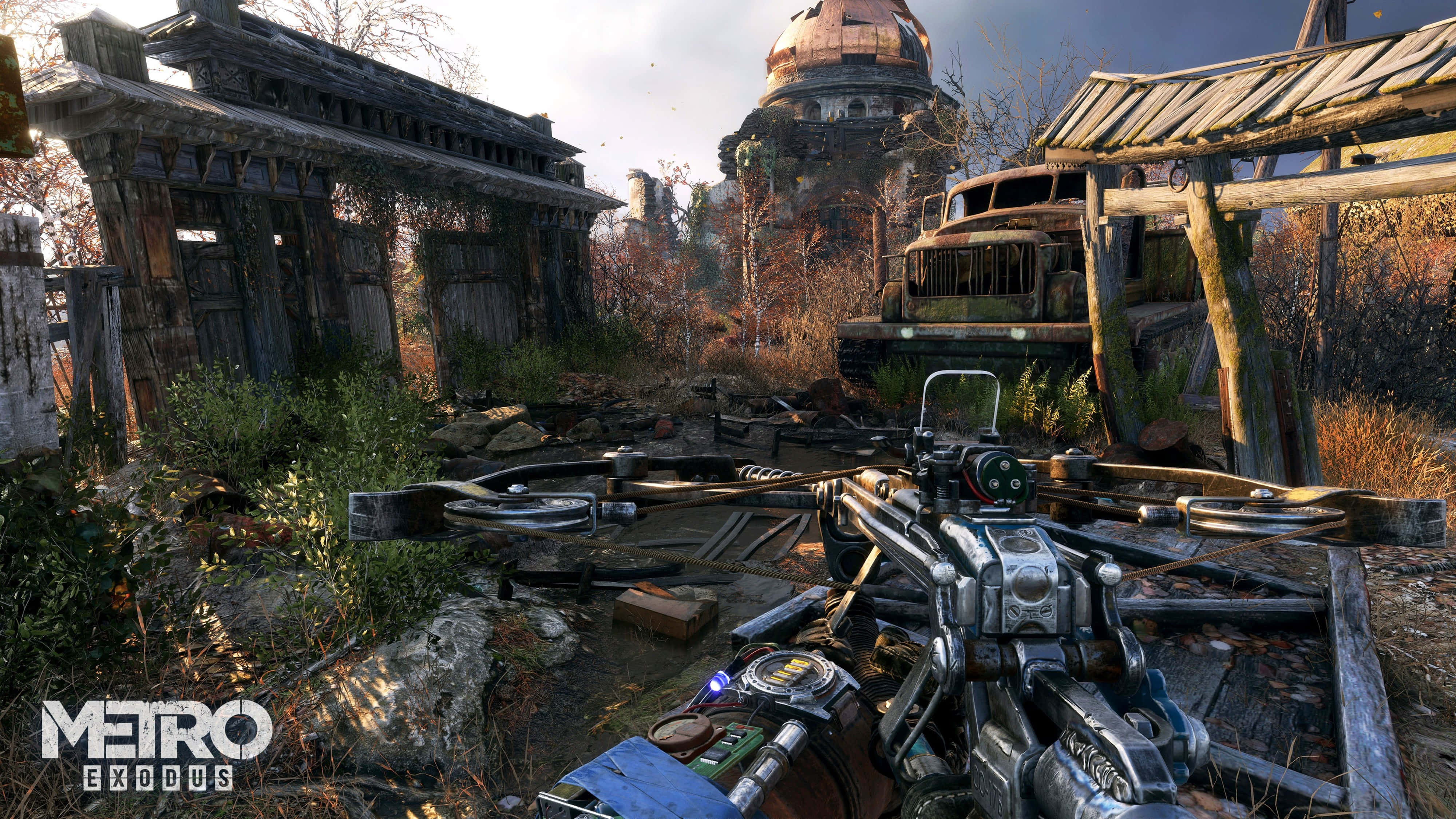 探索《Metro Exodus》4K 中的末日世界 壁紙 — 廢墟中的末世小鎮，背景有圓頂建築，以第一人稱視角展示十字弓。