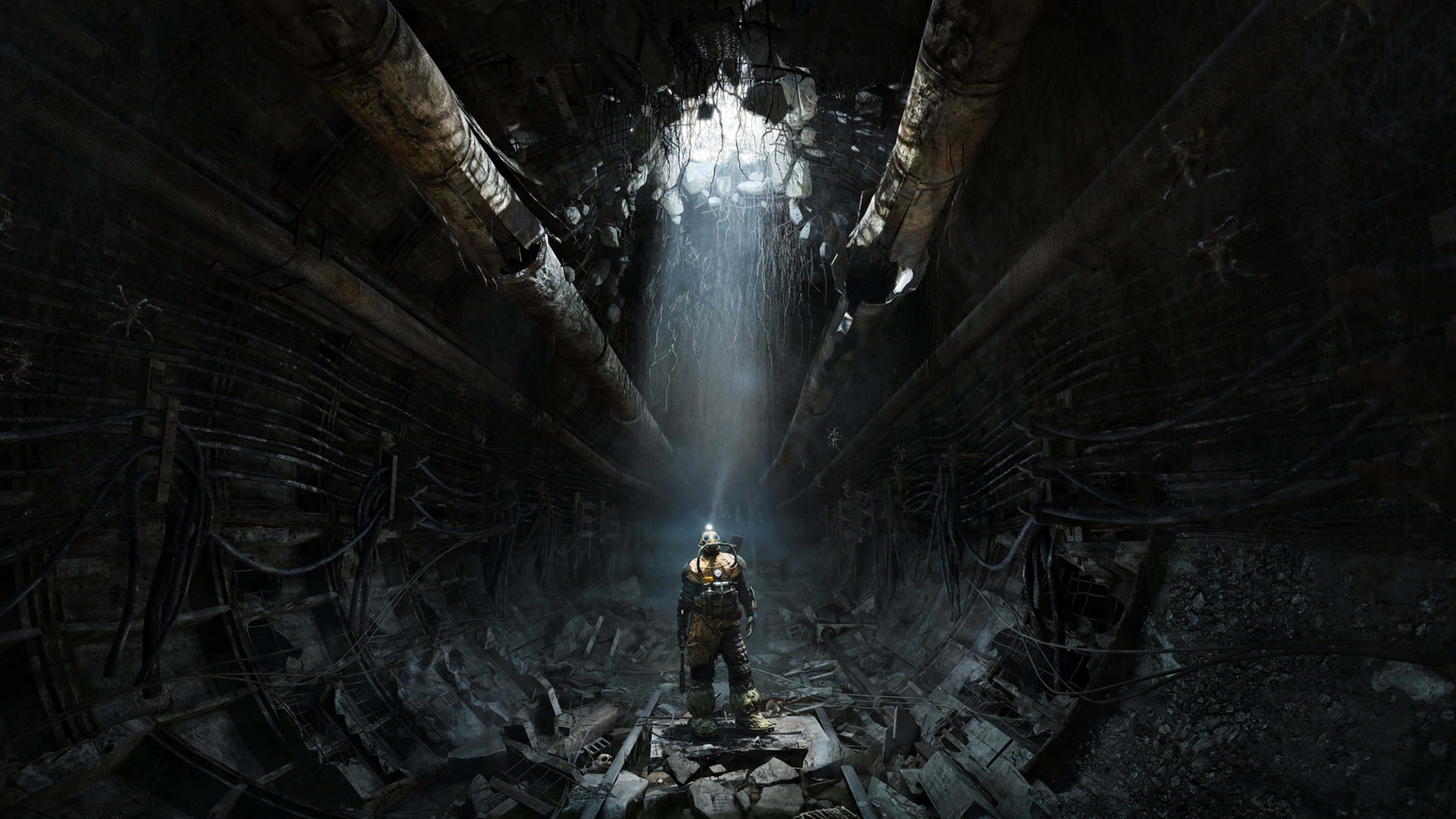 《Metro Exodus》4K 超高解析度遊戲壁紙 壁紙 — 一個孤獨的裝甲身影站在廢墟隧道中，被上方的一束光照亮，周圍是碎片和懸掛的管道。