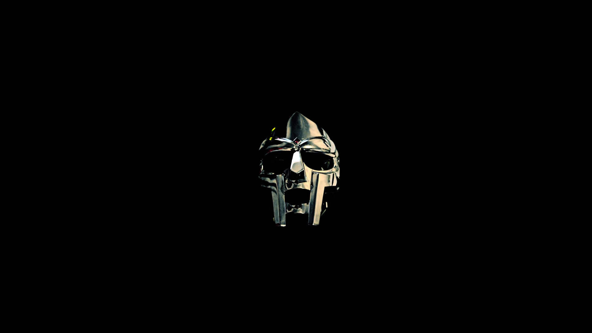 MF Doom頭盔 壁紙 — 一個金屬斯巴達頭盔在漆黑虛空中微微發光，投射出銳利陰影並反射環境光。