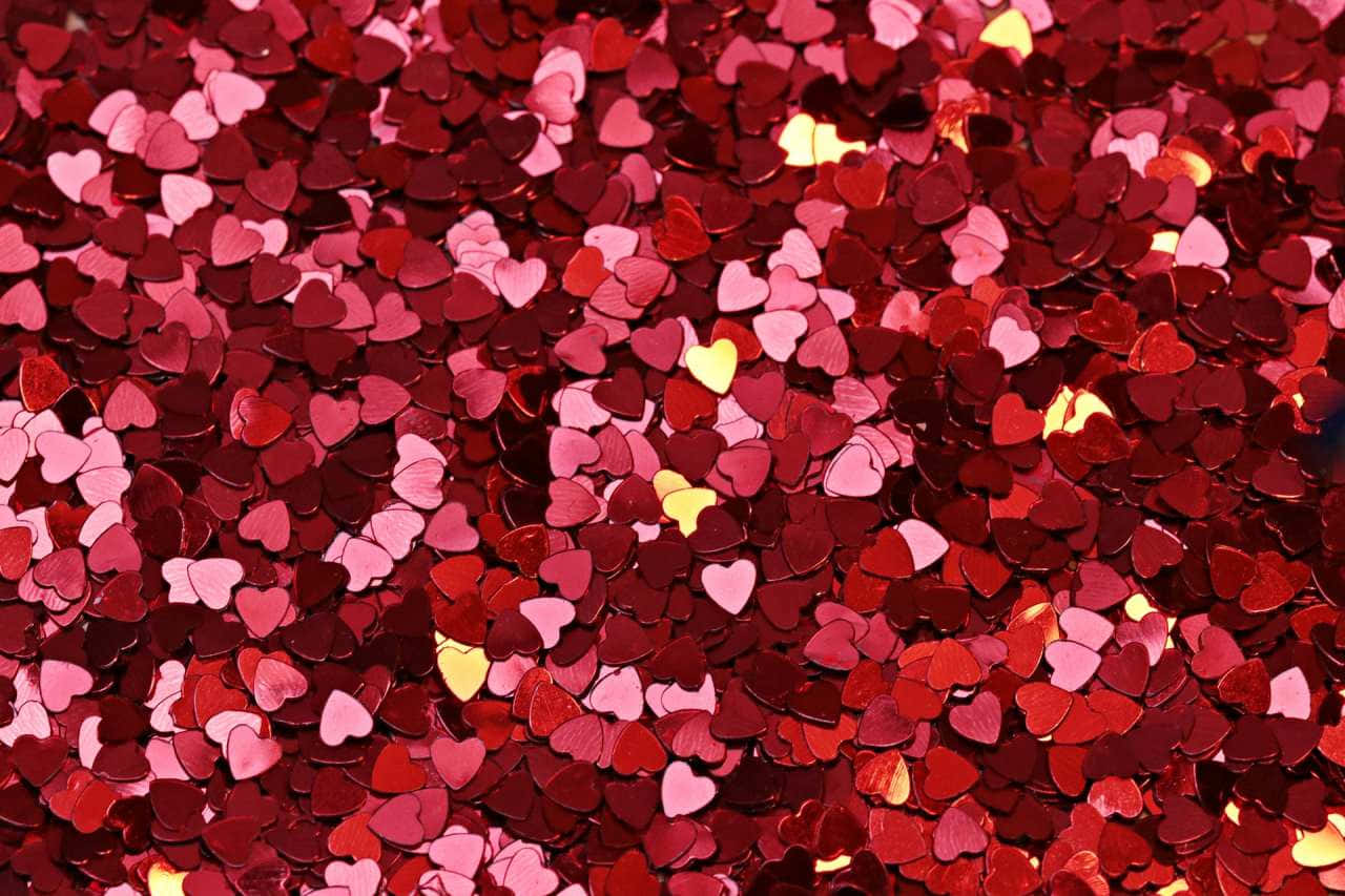 散落的紅色、粉紅色和黃色心形亮片特寫。 — 粉紅色心形動圖 壁紙