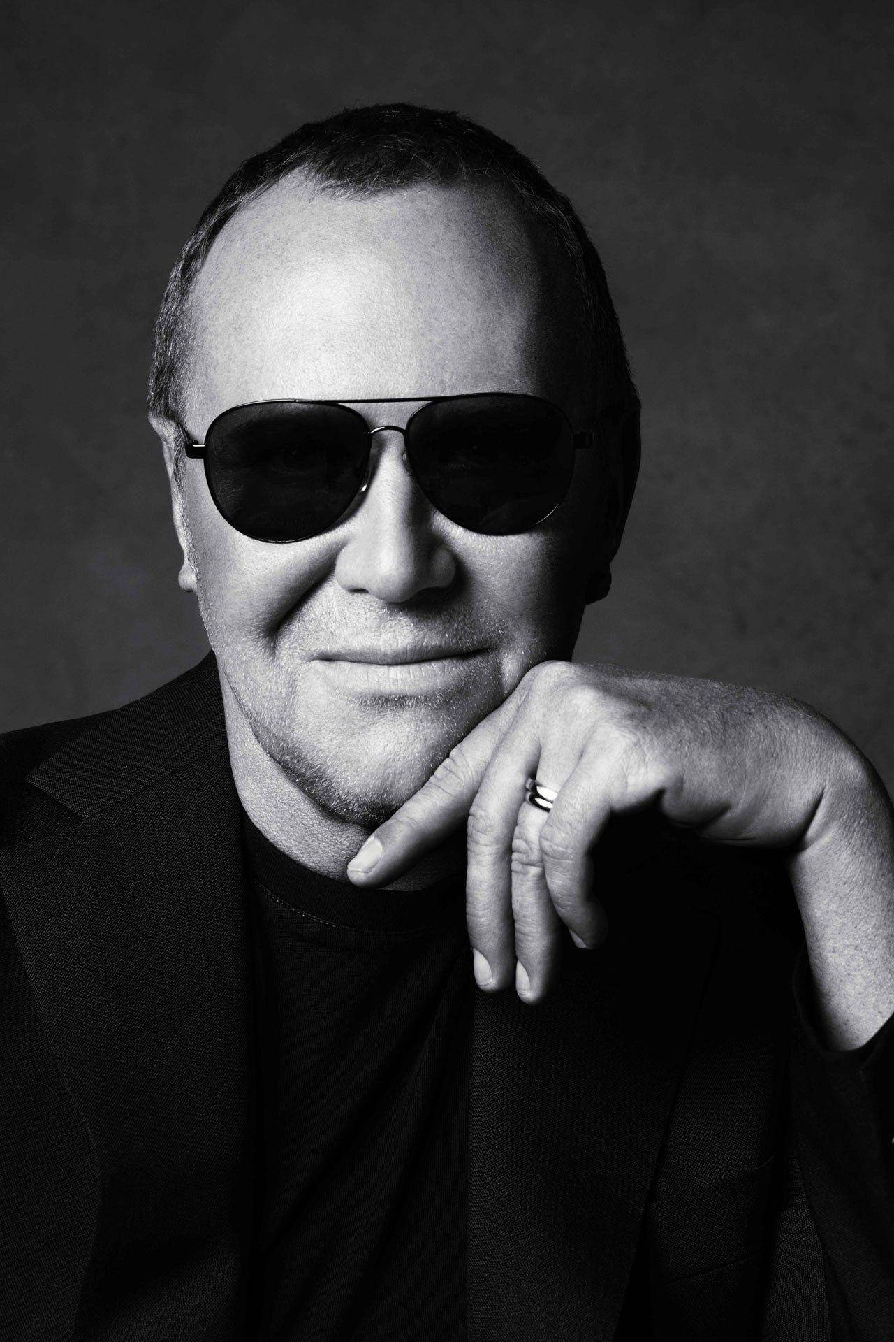 Michael Kors 單色肖像照 壁紙 — 一個黑白肖像，一名戴著太陽眼鏡的男子，手托著下巴，背景是深色有紋理的。