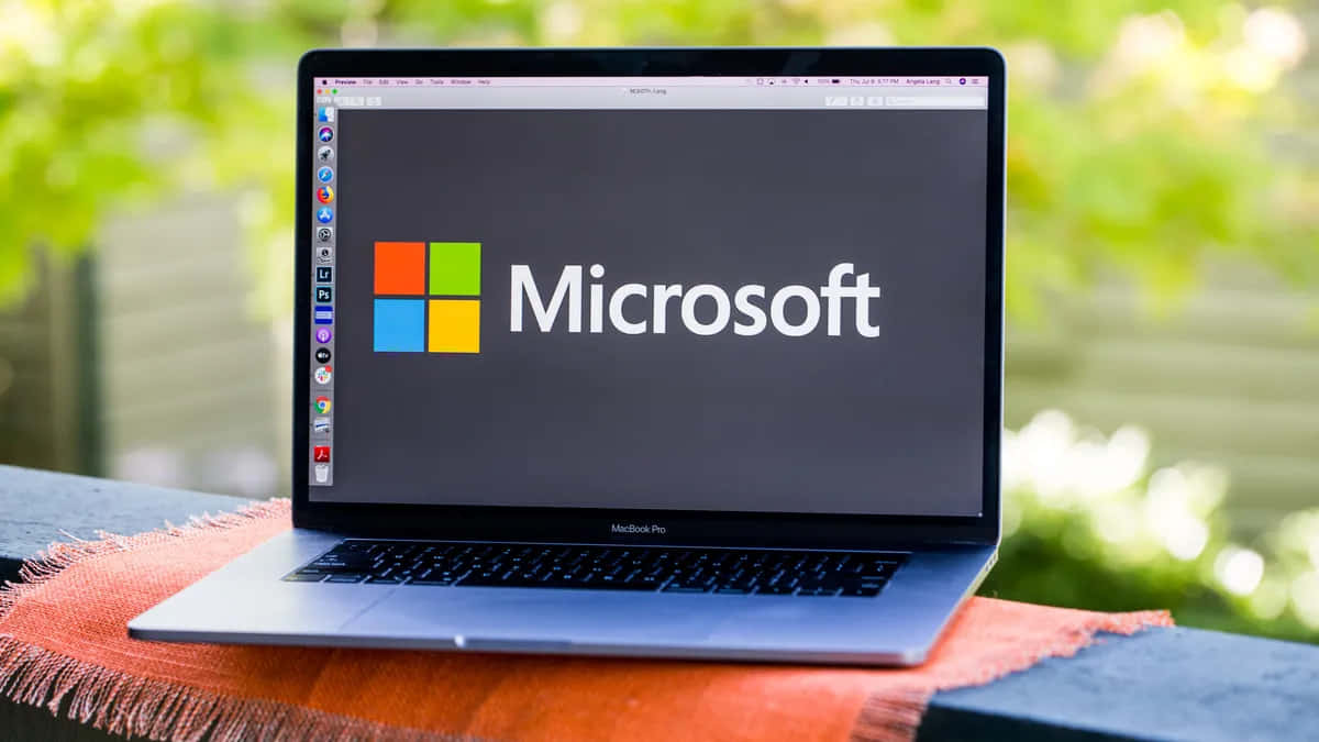 銀色手提電腦在屏幕上顯示Microsoft標誌，放在橙色布上戶外。