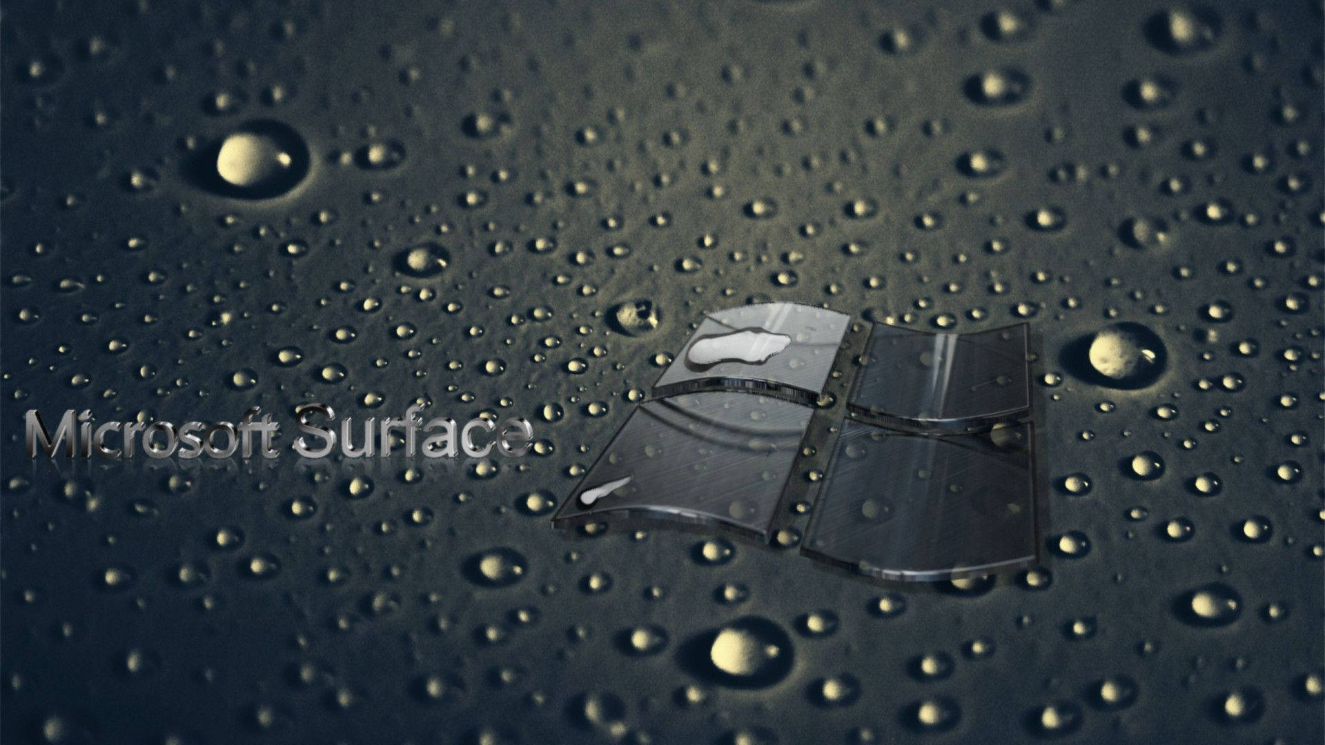 microsoft 桌布 壁紙 — Microsoft Surface 標誌部分浸沒在深色反光表面的水滴中。