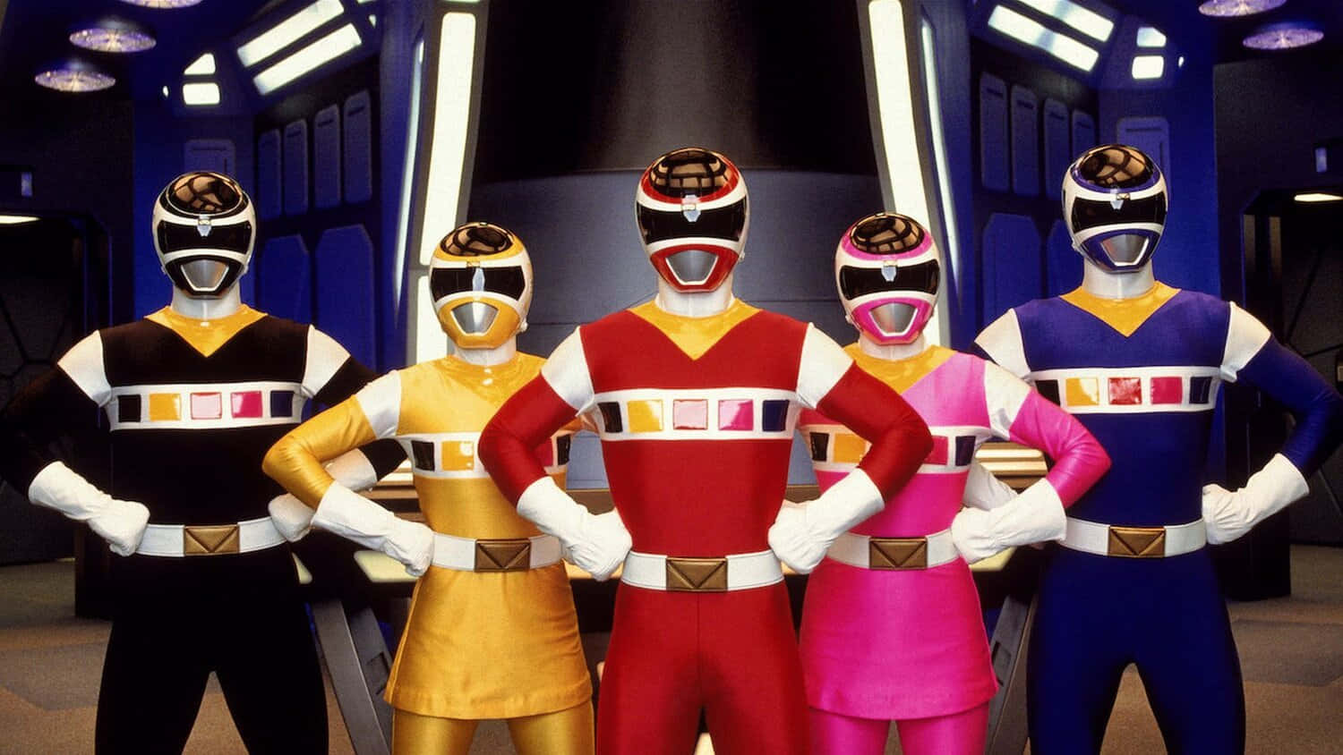 Mighty Morphin Power Rangers令邪惡聞風喪膽 壁紙 — 五位穿著色彩繽紛服裝的恐龍戰隊在一個帶有發光面板的未來主義指揮中心中自信地站立。