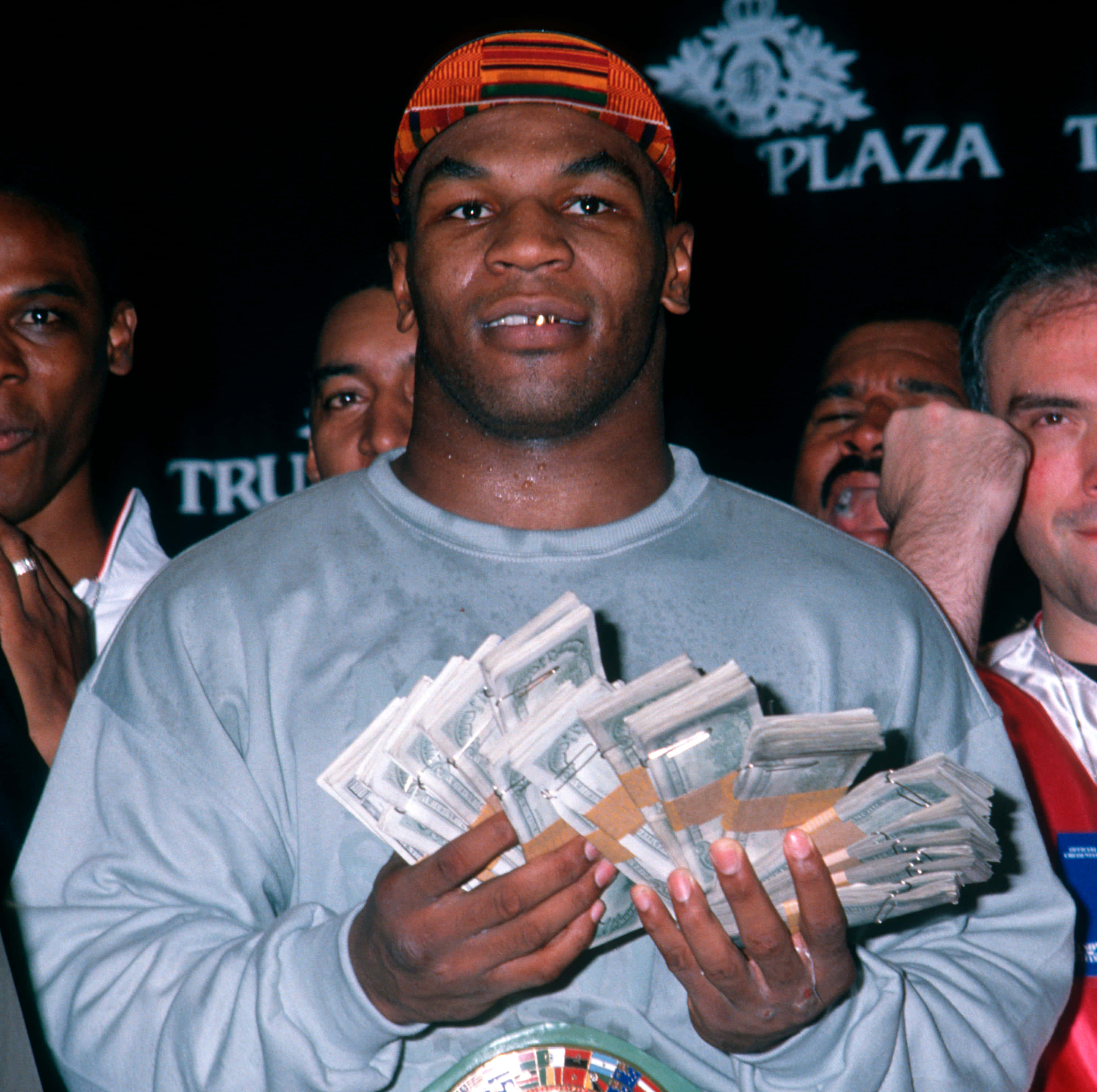 mike tyson 桌布 壁紙 — Mike Tyson 喺 Plaza 活動中自豪咁微笑，手揸一疊疊現金，周圍有人。