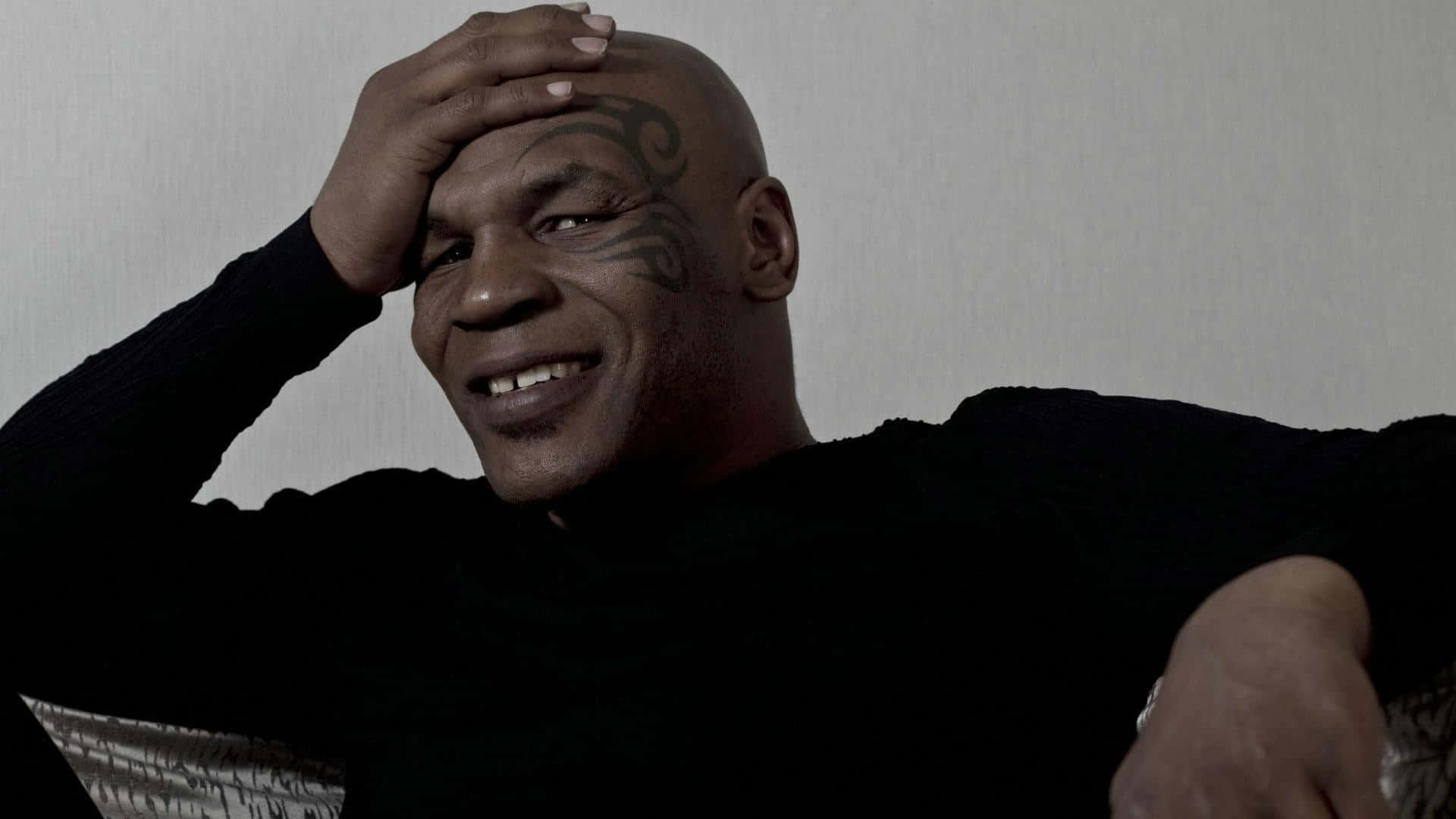mike tyson 桌布 壁紙 — Mike Tyson 溫暖地微笑，將手放在頭上靠著素牆。
