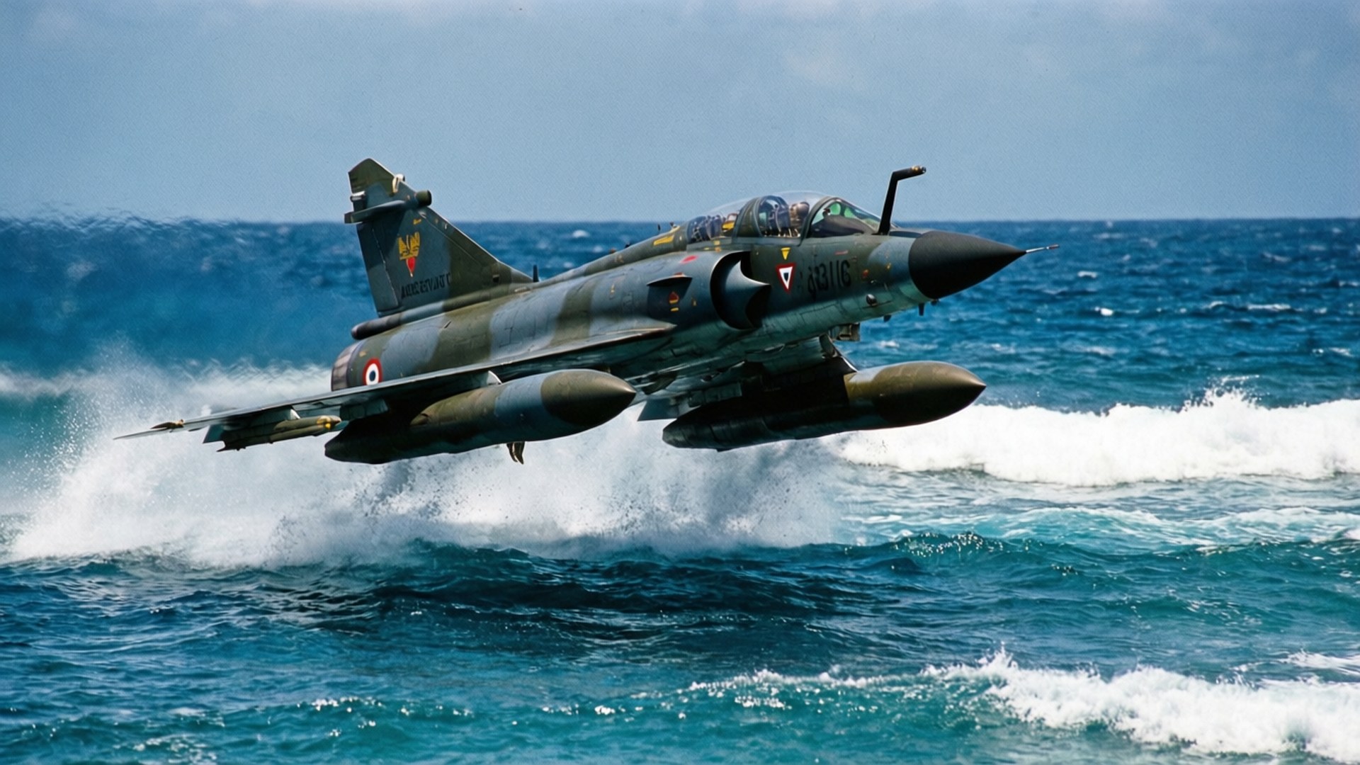 Dassault Mirage III 桌布 壁紙 — 一架帶有迷彩塗裝的軍用噴射機從海浪中起飛，在清澈的藍天下產生白色水花。