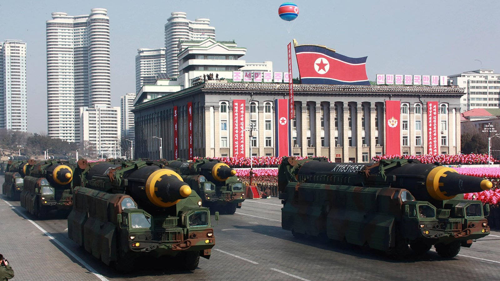 載有導彈的軍用車輛在朝鮮城市中在國旗下遊行。