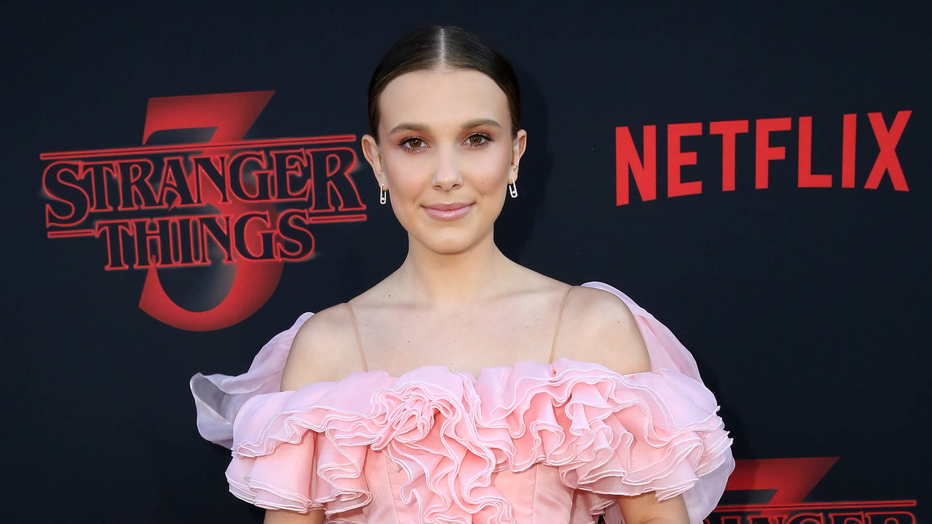 在Stranger Things Netflix活動中穿著粉紅色荷葉邊連衣裙的女性。