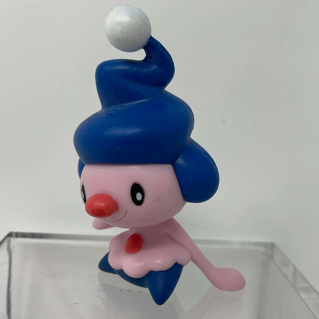 Mime Jr. 玩偶 壁紙 — 一個粉紅色和藍色的寵物小精靈公仔，戴著螺旋帽，頂部有一個白色球，站在透明展示架上，背景是純白色。