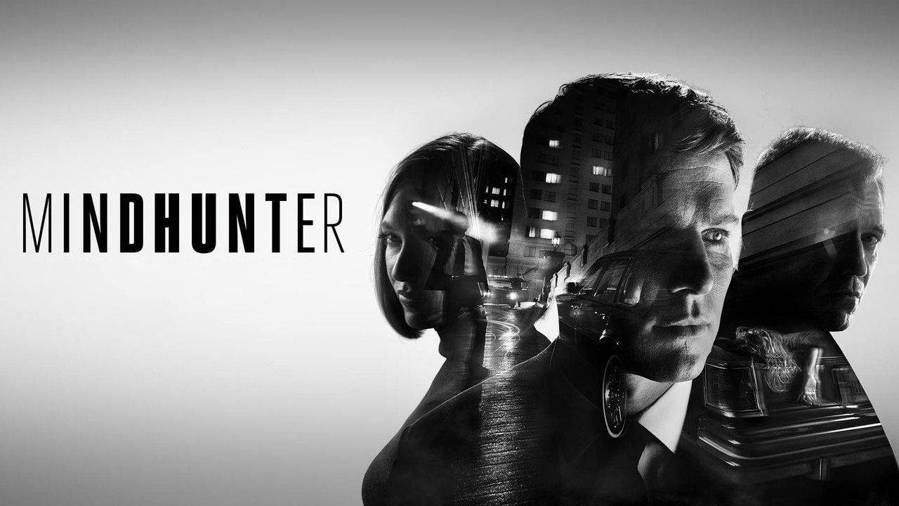 《Mindhunter》劇集海報主角群 壁紙 — Mindhunter 的黑白宣傳海報，三個表情強烈的面孔疊加在夜景城市景觀上。