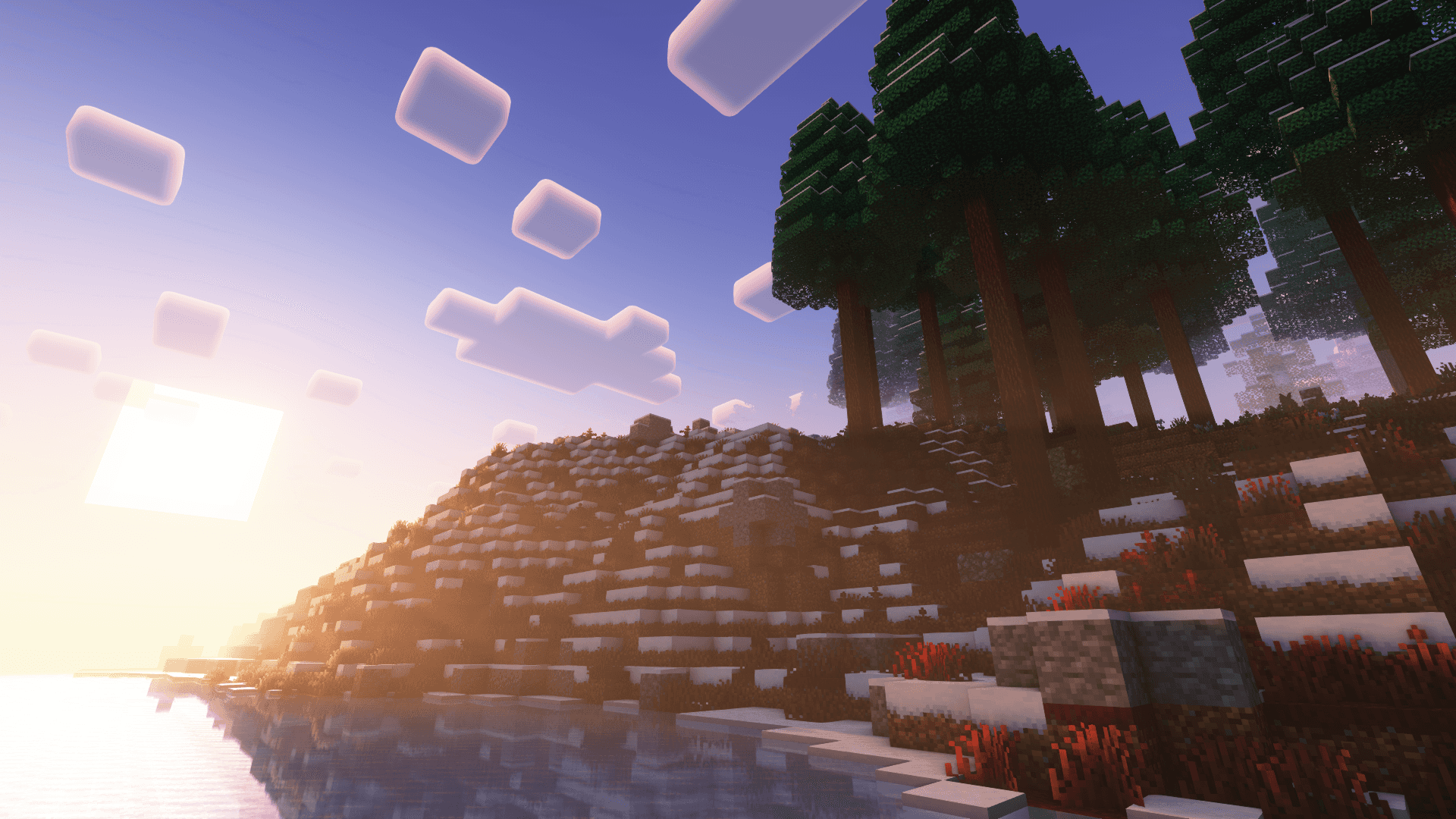 Minecraft 冬日夕陽旁的樹林 壁紙 — 夕陽落在積雪的Minecraft山丘上，像素化的樹木和漂浮的雲朵倒映在平靜的水面上。