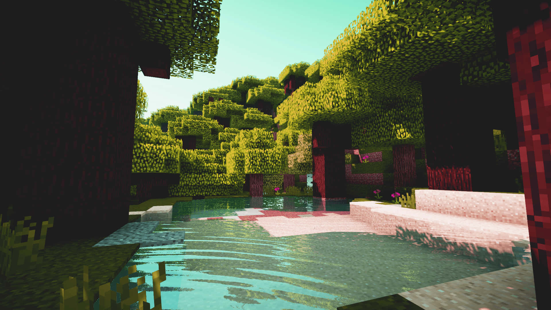 用Minecraft Shaders看見與創造美麗世界 壁紙 — 一個像素化的Minecraft場景，清澈的泳池被茂密的綠樹和紅磚建築環繞，天空明亮。