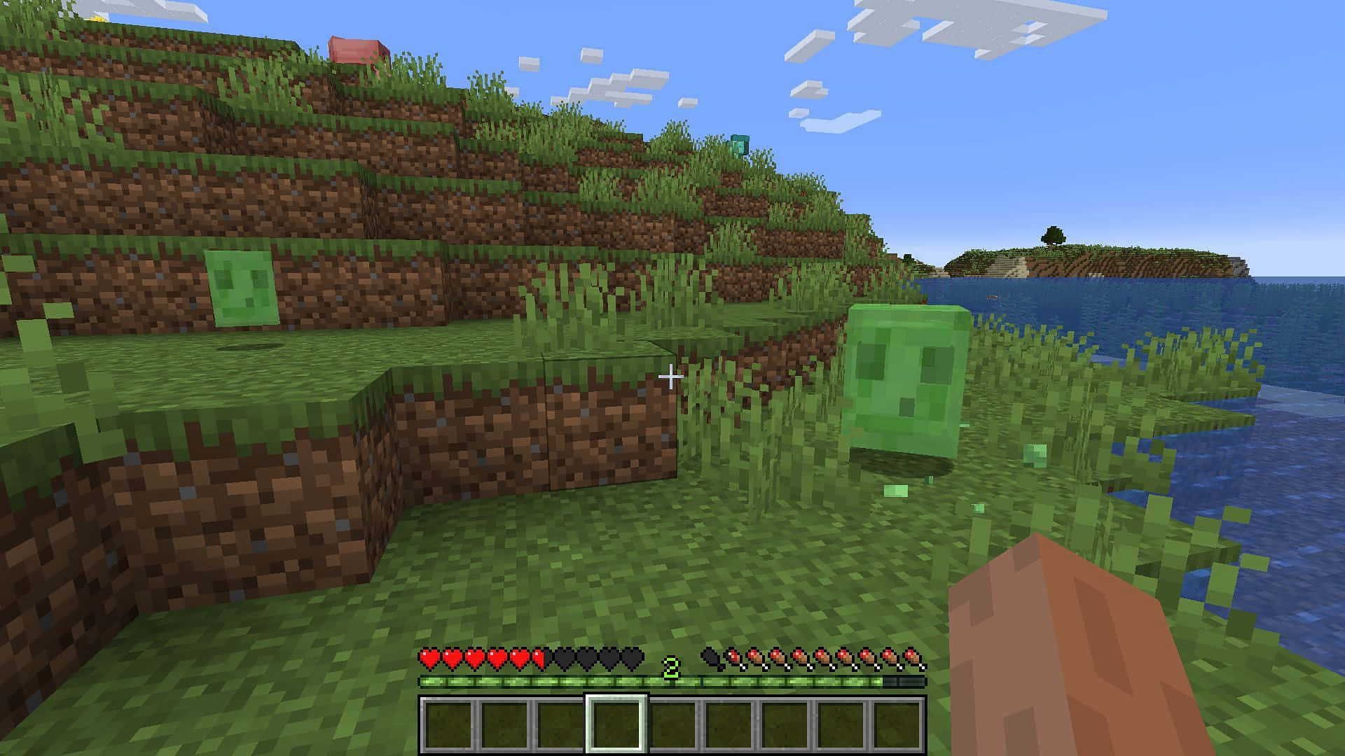 Minecraft Survival 桌布 壁紙 — Minecraft 第一人稱視角，顯示綠色爬行者靠近草地丘陵和水邊，藍天白雲。