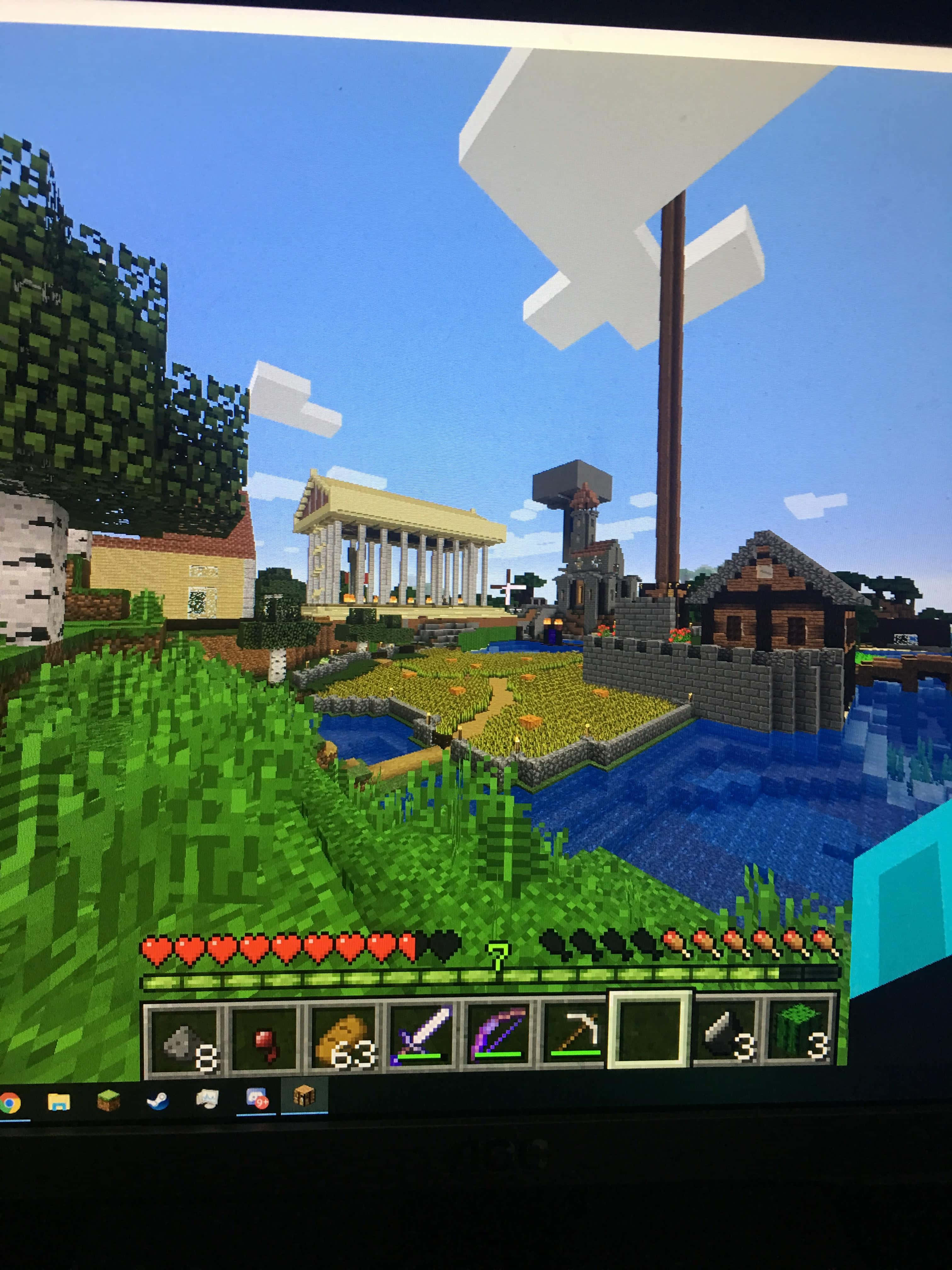 Minecraft Server 桌布 壁紙 — Minecraft 遊戲場景，包含像素化草地、水和建築物，背景是藍天白雲。