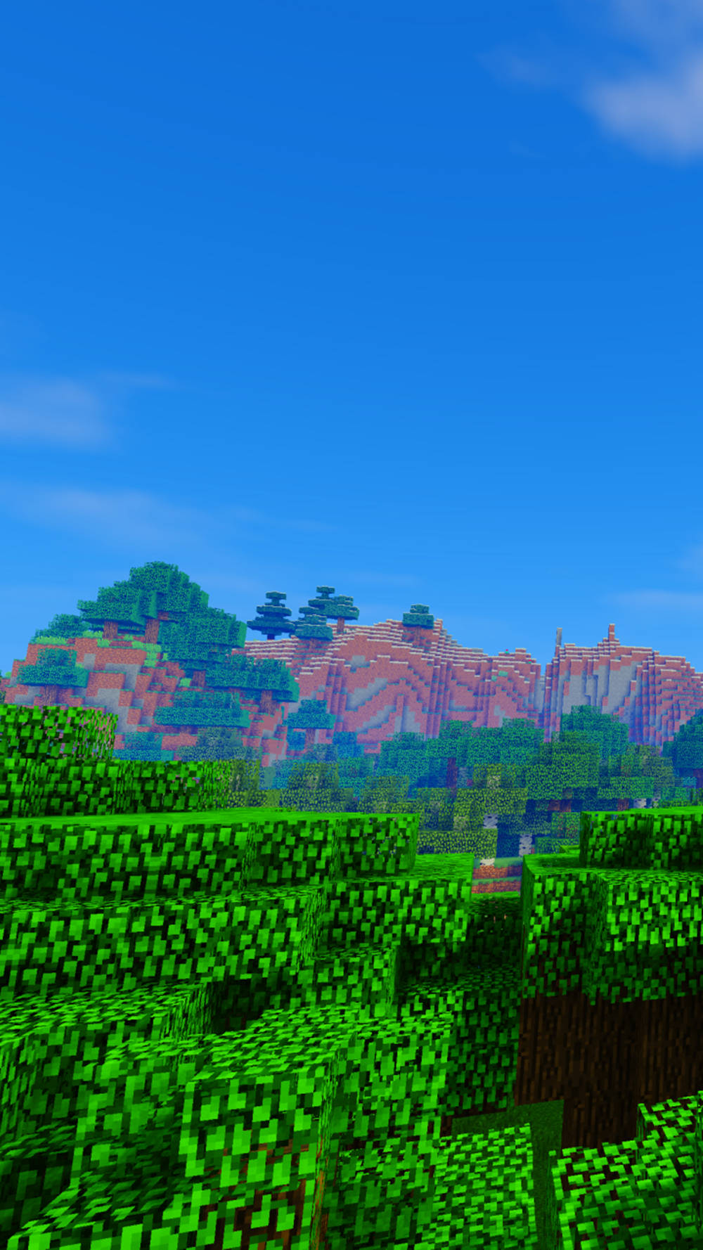 藍天下有綠色樹木和紅色山脈的Minecraft遊戲場景