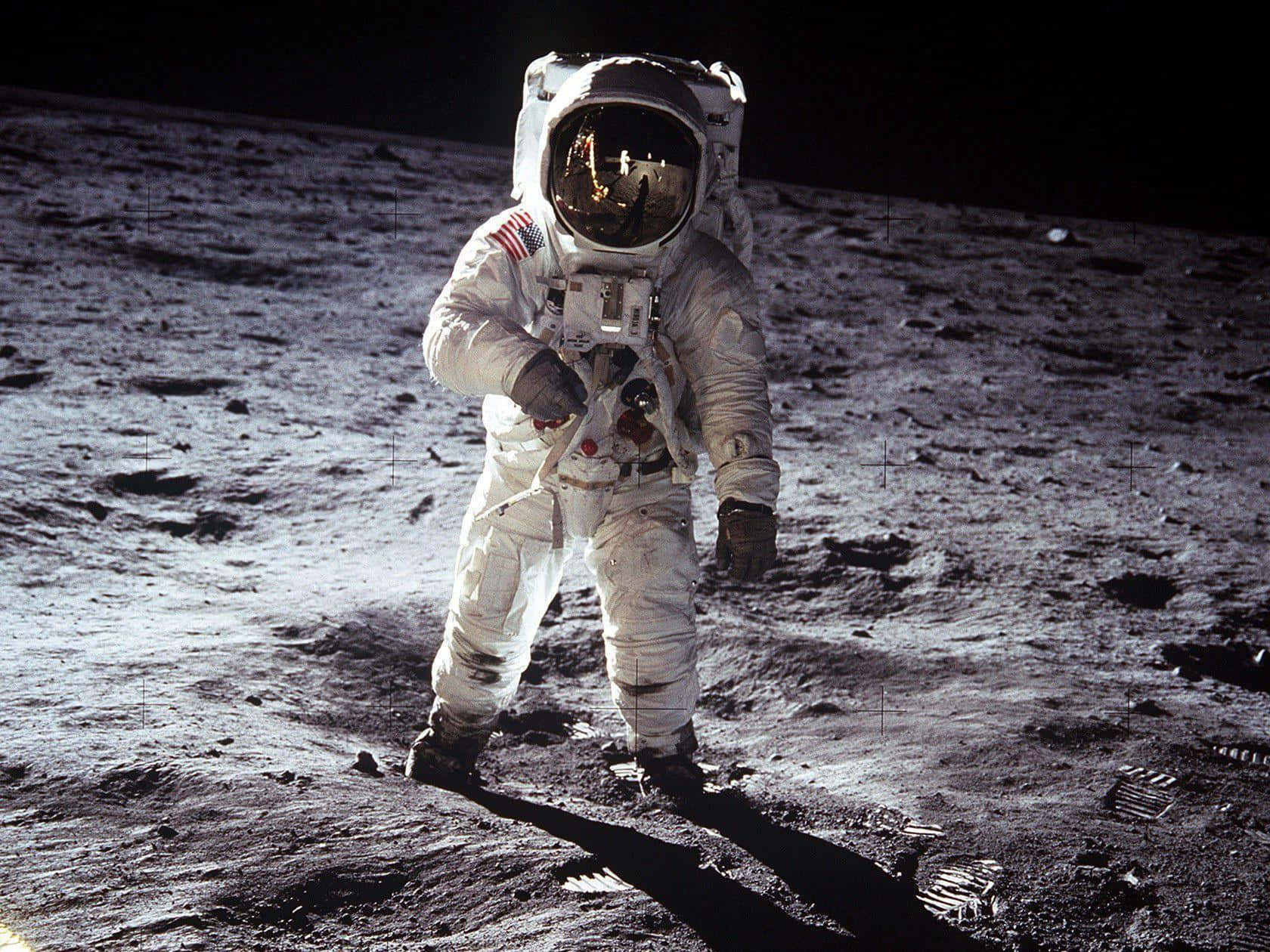 Neil Armstrong 桌布 壁紙 — 一名身穿白色太空衣的太空人站在月球灰色的表面上，在明亮的陽光下投下長長的影子。