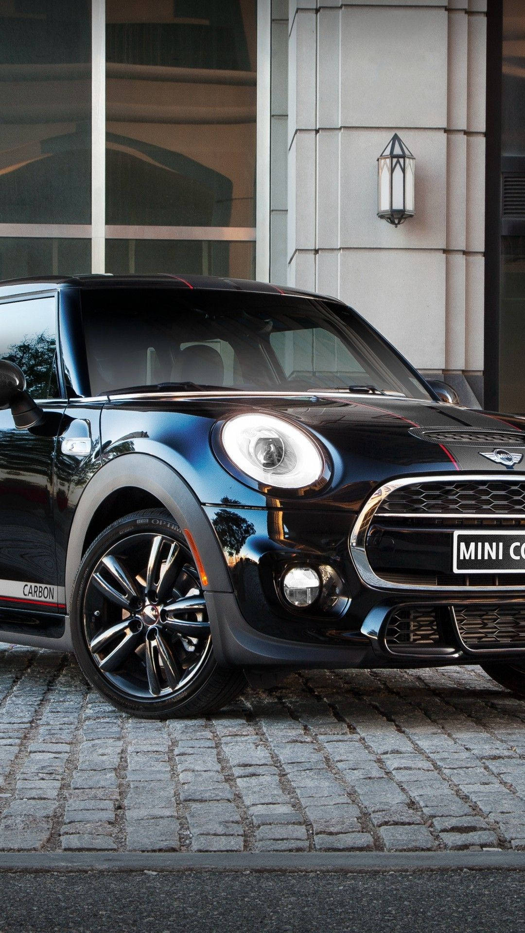 黑色MINI Cooper停泊在現代建築附近的鵝卵石街道上