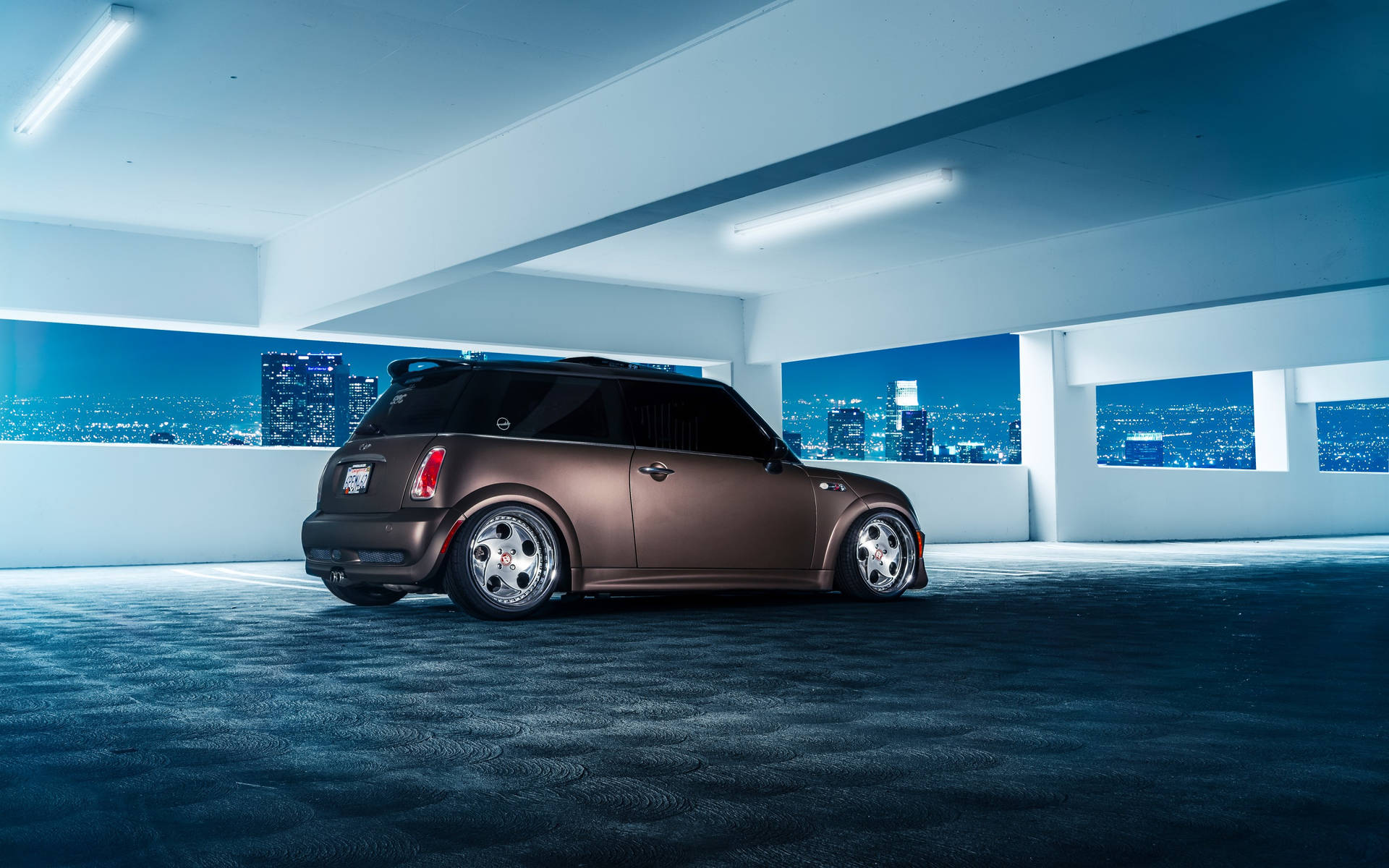 青銅色Mini Cooper停在天台車庫，夜晚城市燈光。