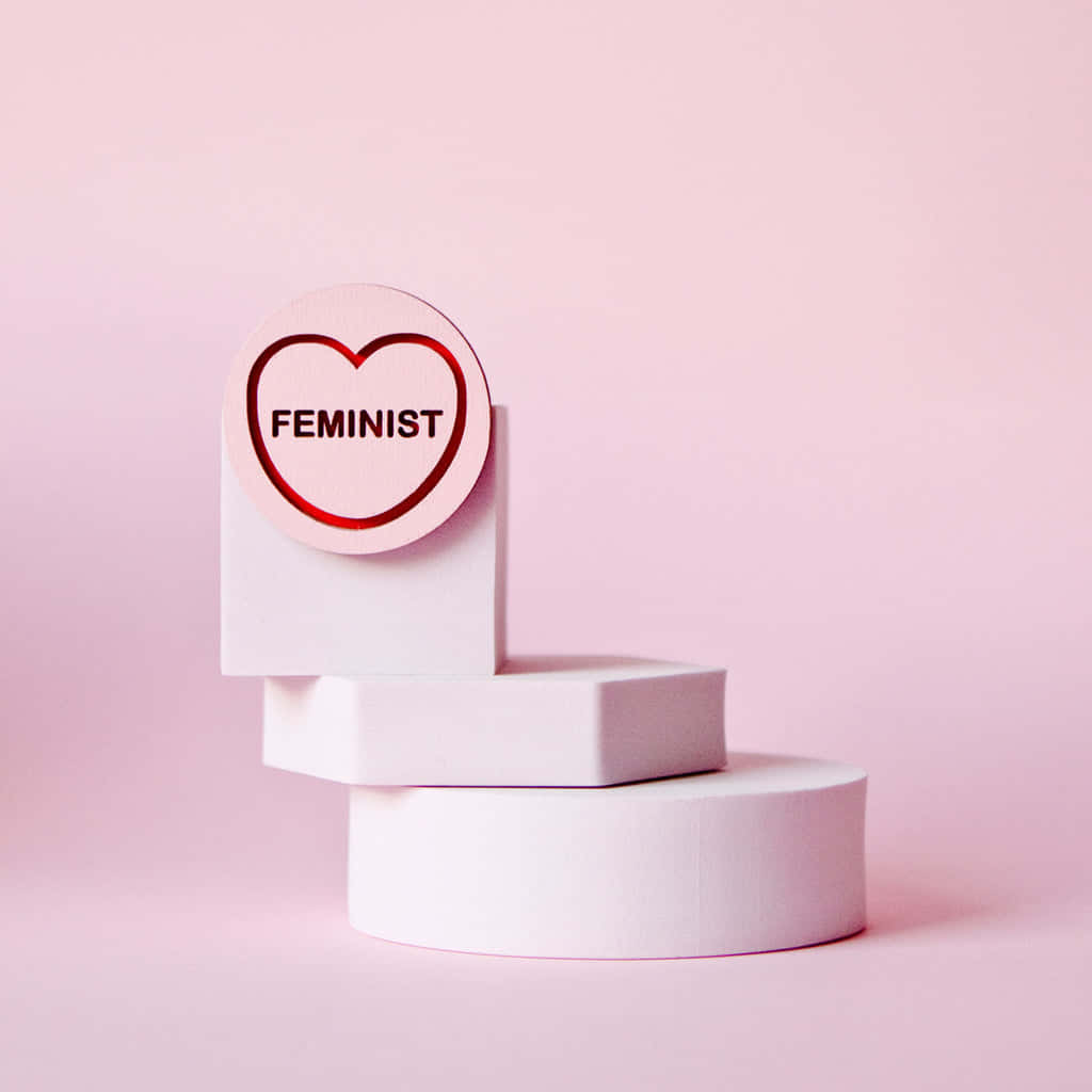 一個粉紅色的心形，上面寫著「feminist」，放在白色積木上，背景是粉紅色。 — 粉紅色心形動圖 壁紙