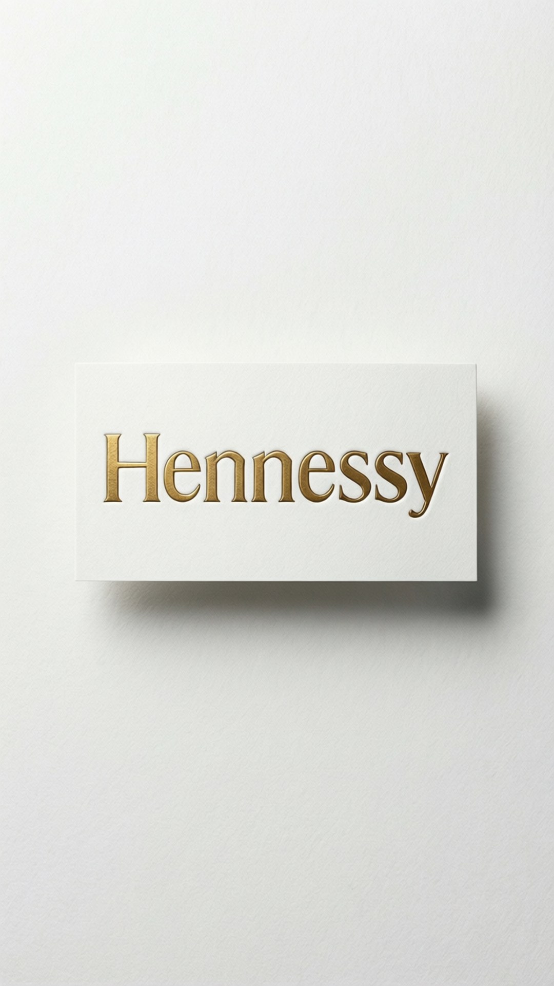 白色卡片，帶有金色Hennessy標誌，安裝在紋理白色牆上