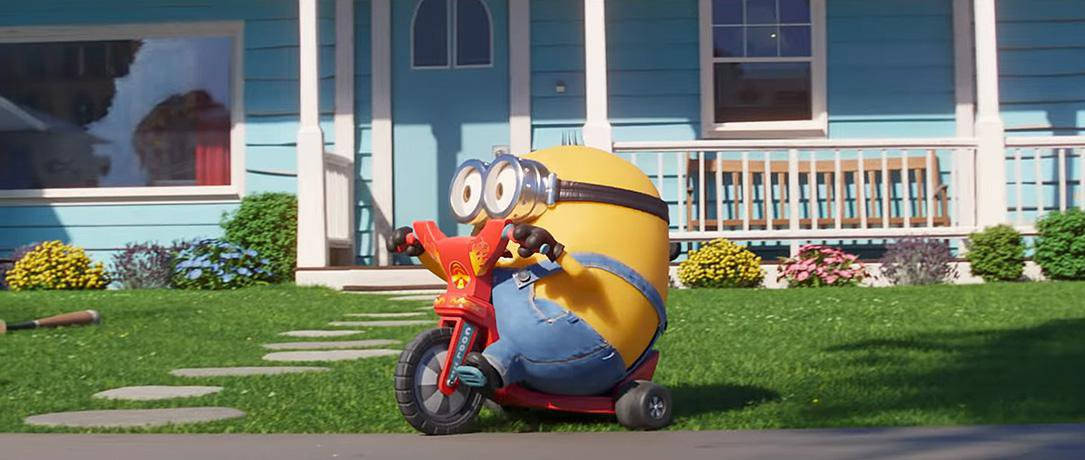 黃色Minion在藍色房子前的綠色草坪上騎紅色三輪車