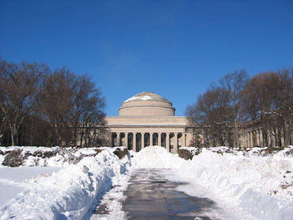 積雪的小路通向一座宏偉的圓頂大學建築，背景是清澈的藍天。